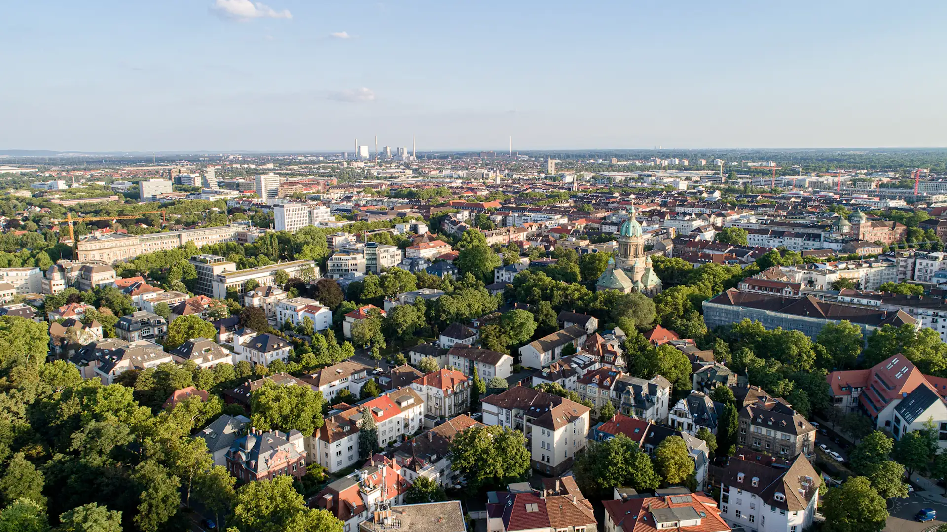 Luftaufnahme einer Stadt mit vielen Wohnhäusern, Bäumen und einer großen Kirche in der Mitte.