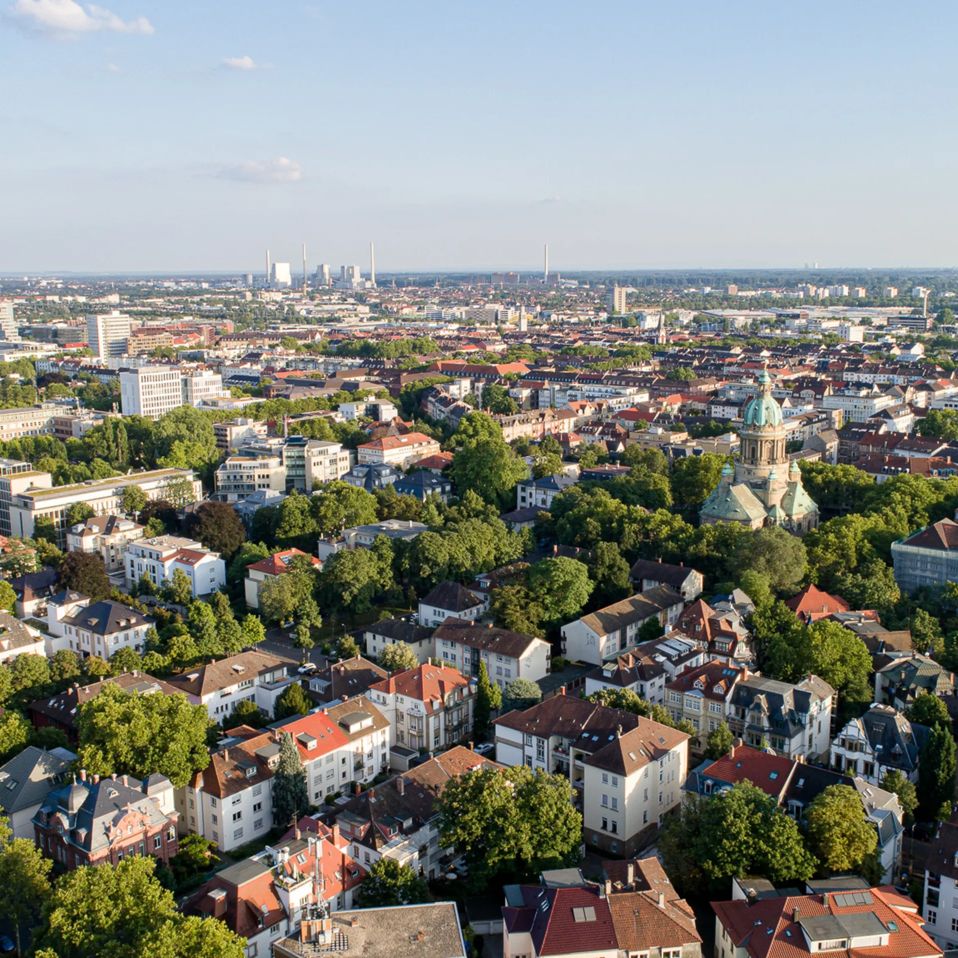 Luftaufnahme einer Stadt mit vielen Wohnhäusern, Bäumen und einer großen Kirche in der Mitte.
