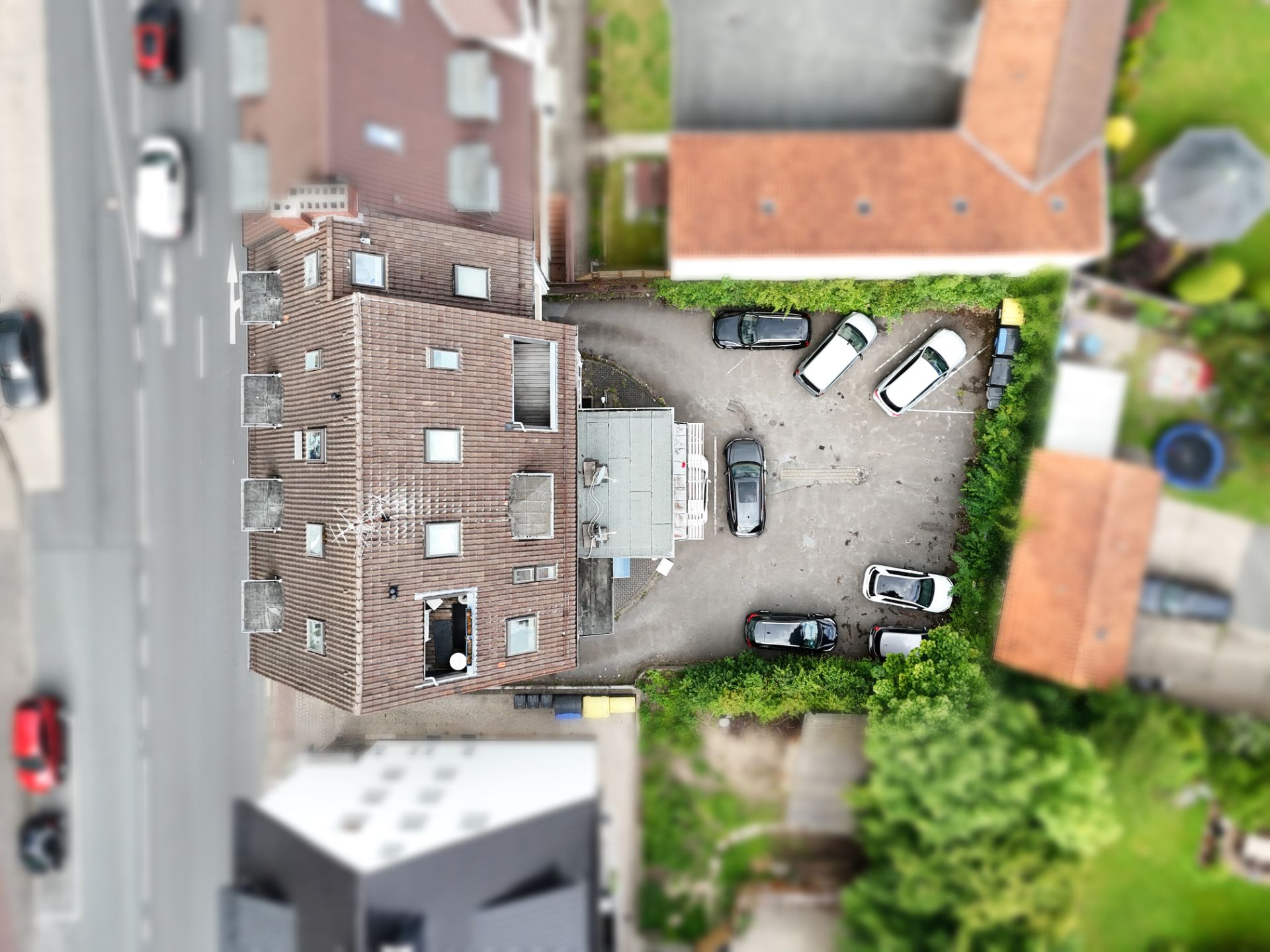 Luftbild eines Wohngebäudes mit mehreren geparkten Autos auf dem Hof.