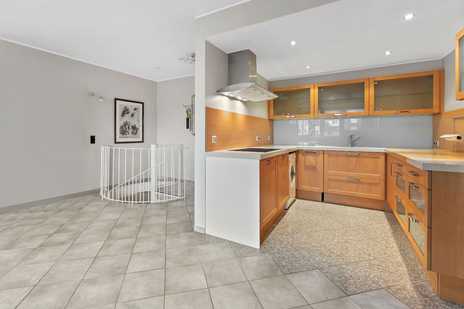 Moderne Küche mit Holzfronten und Glasoberschränken, daneben eine Wendeltreppe mit weißem Geländer.