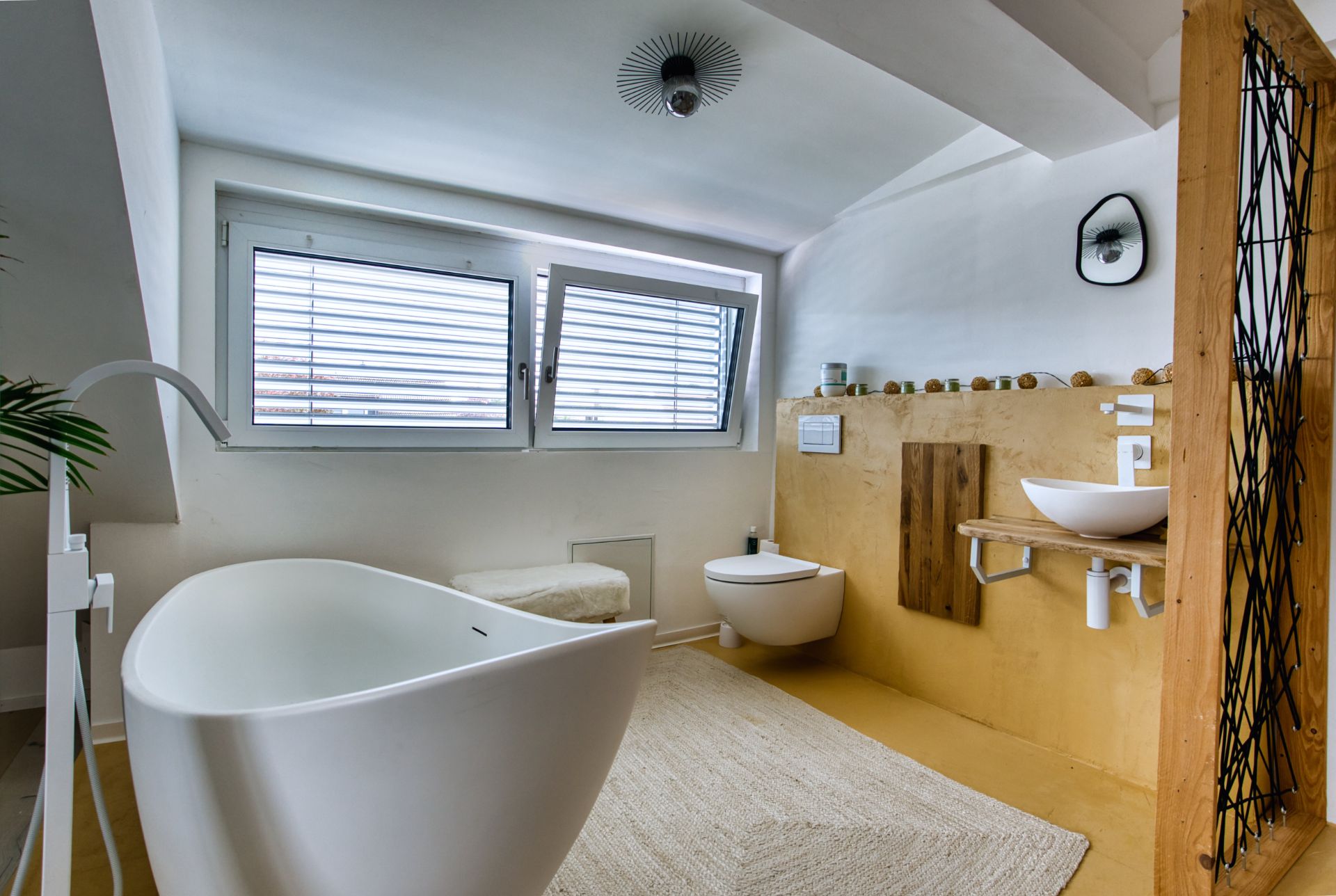 Modernes Badezimmer mit freistehender Badewanne, Waschbecken und WC unter Fenstern.