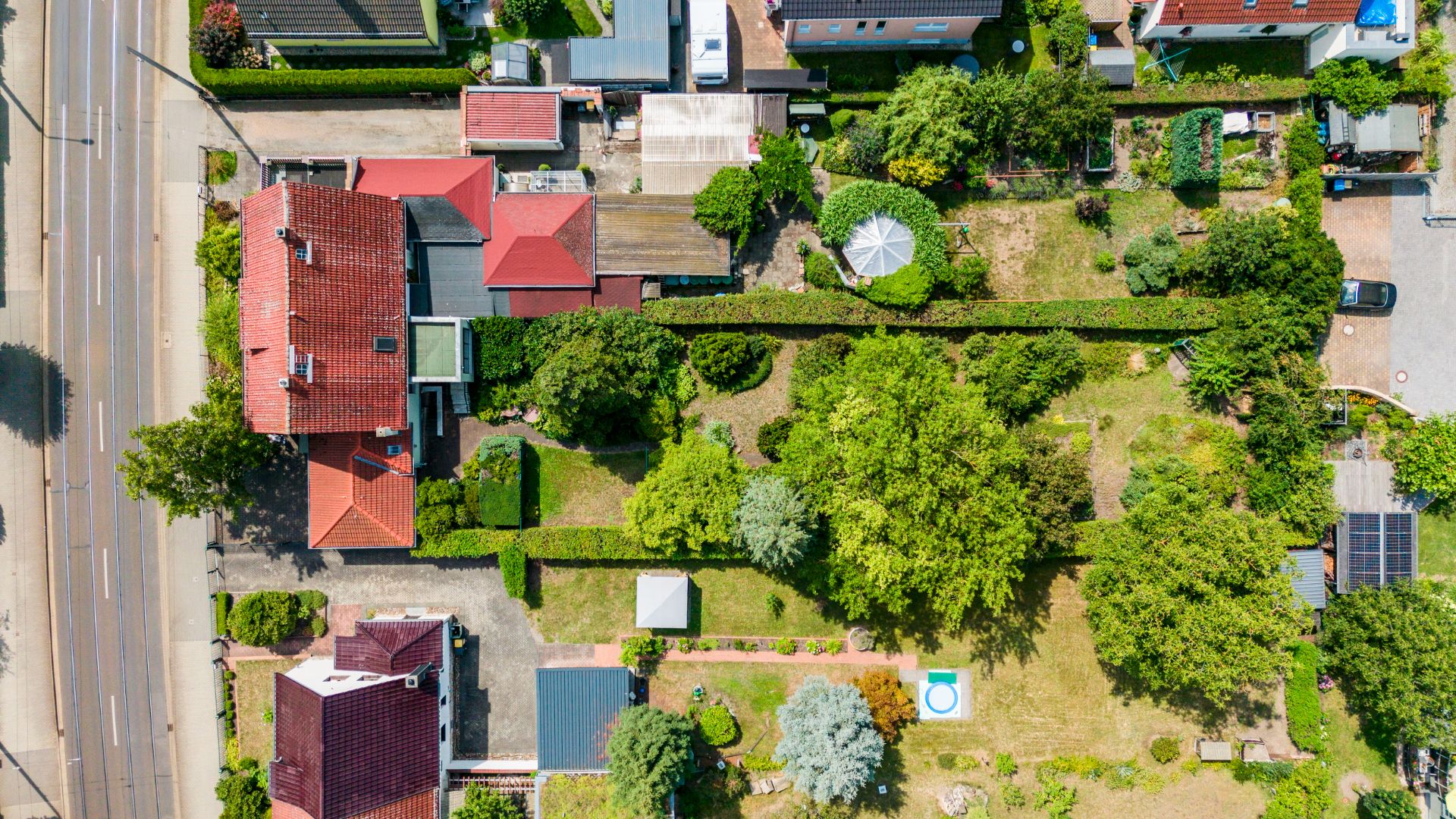 Luftaufnahme von mehreren Häusern mit roten Dächern und großen grünen Gärten.