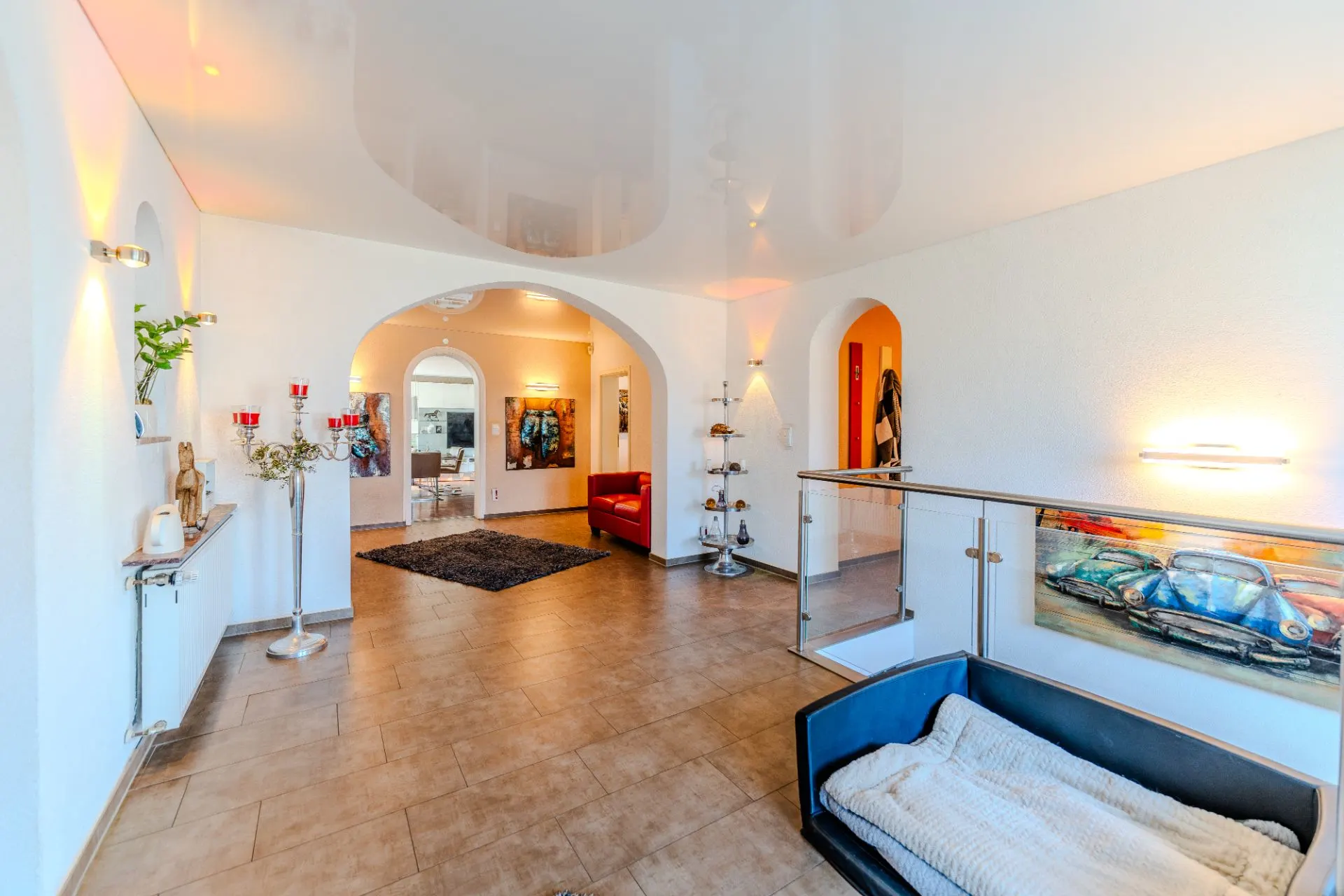 Heller Flur mit Bodenfliesen, Wanddeko, Hundebett und rotem Sessel in einer modernen Wohnung.
