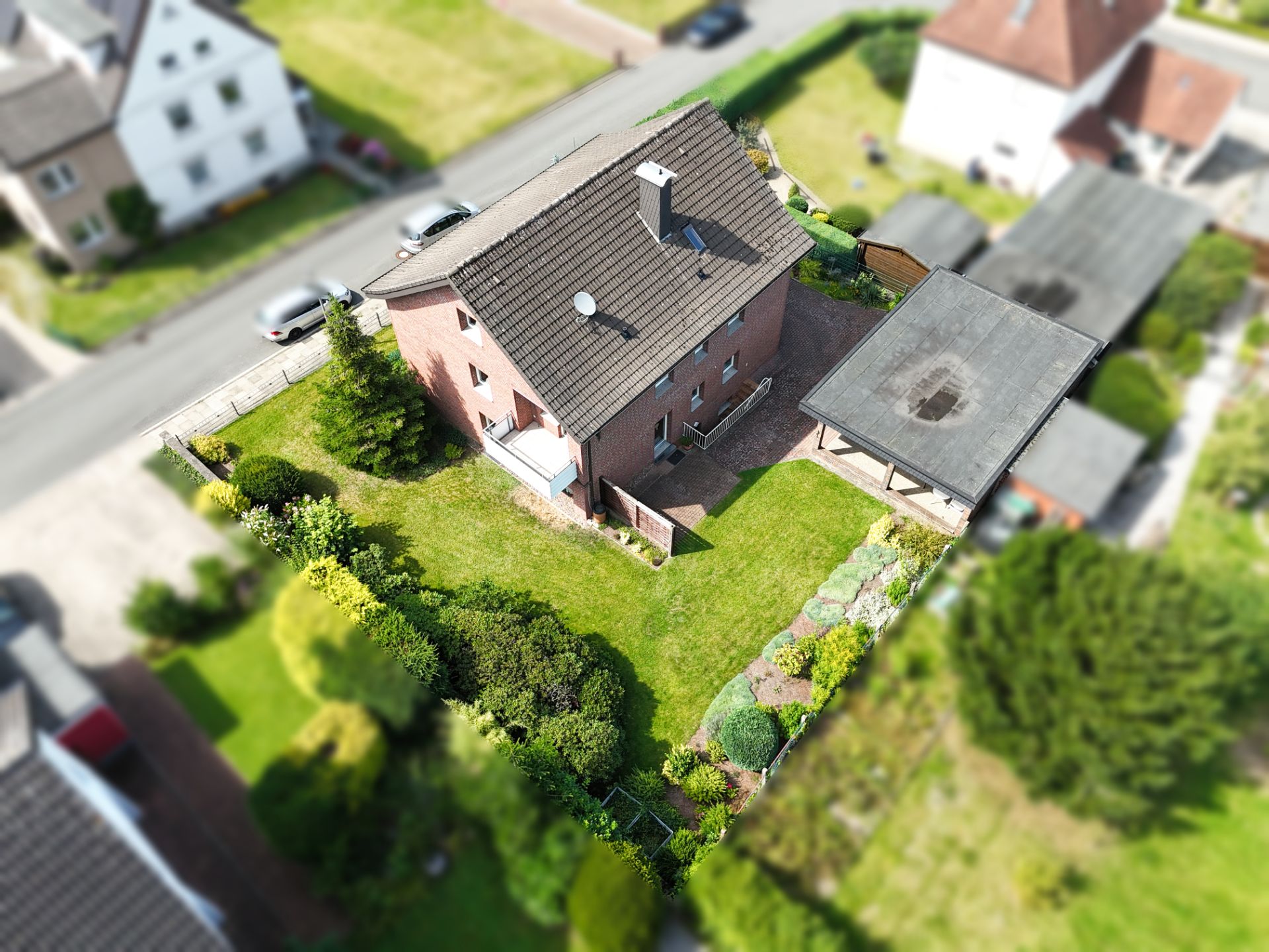 Luftaufnahme eines Einfamilienhauses mit Garten und Carport in einer Wohngegend.