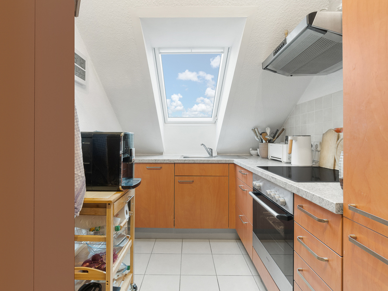 Moderne Einbauküche mit Holzfronten und Dachfenster, Küchengeräten auf der Arbeitsfläche.