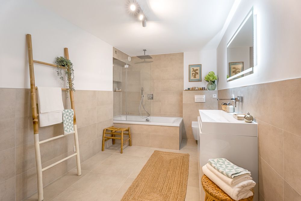 Modernes Badezimmer mit Badewanne, Waschbecken, Leiter als Handtuchhalter und heller Beleuchtung.