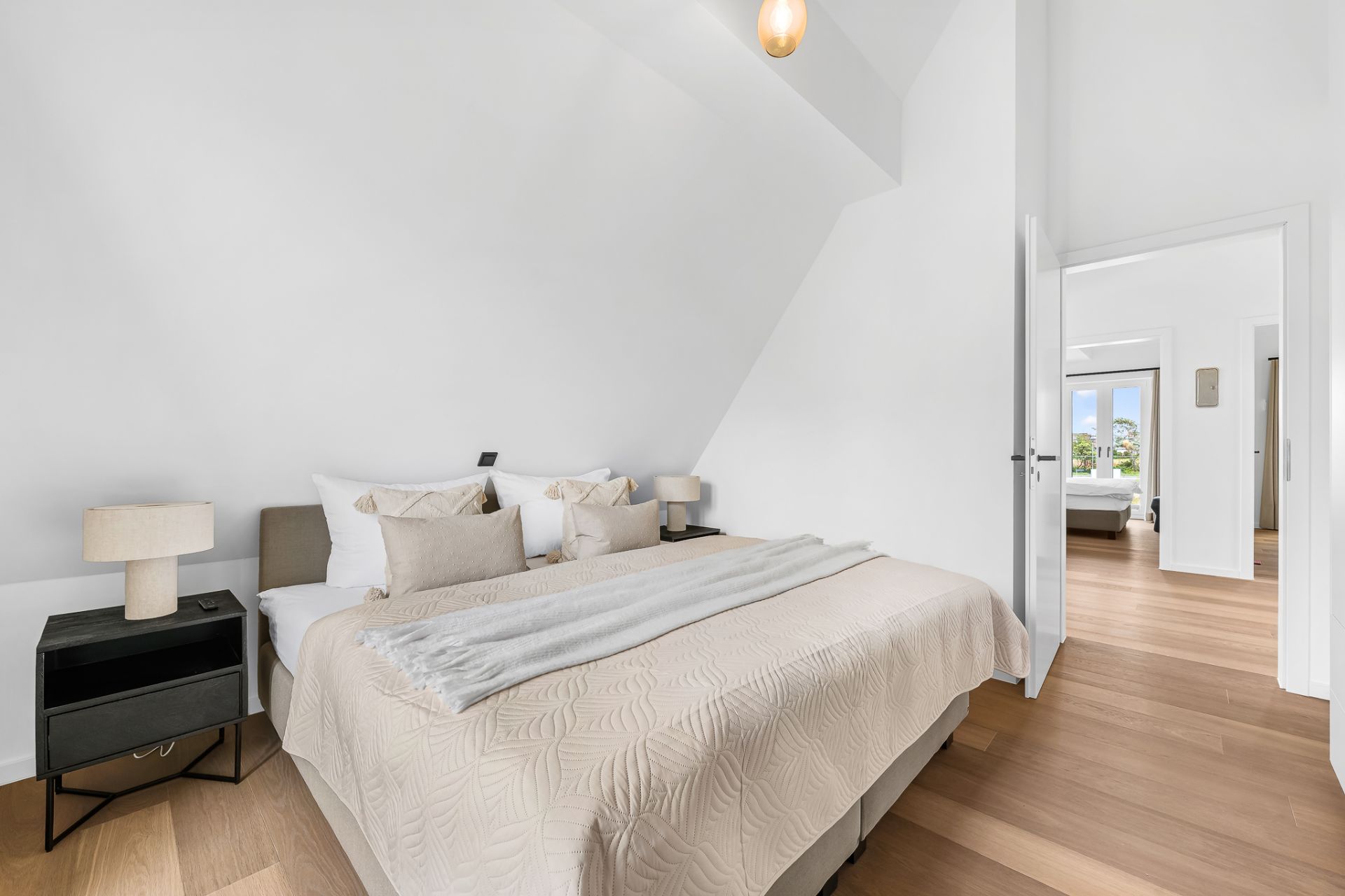 Helles Schlafzimmer mit Doppelbett, zwei Nachttischen und Holzfußboden.