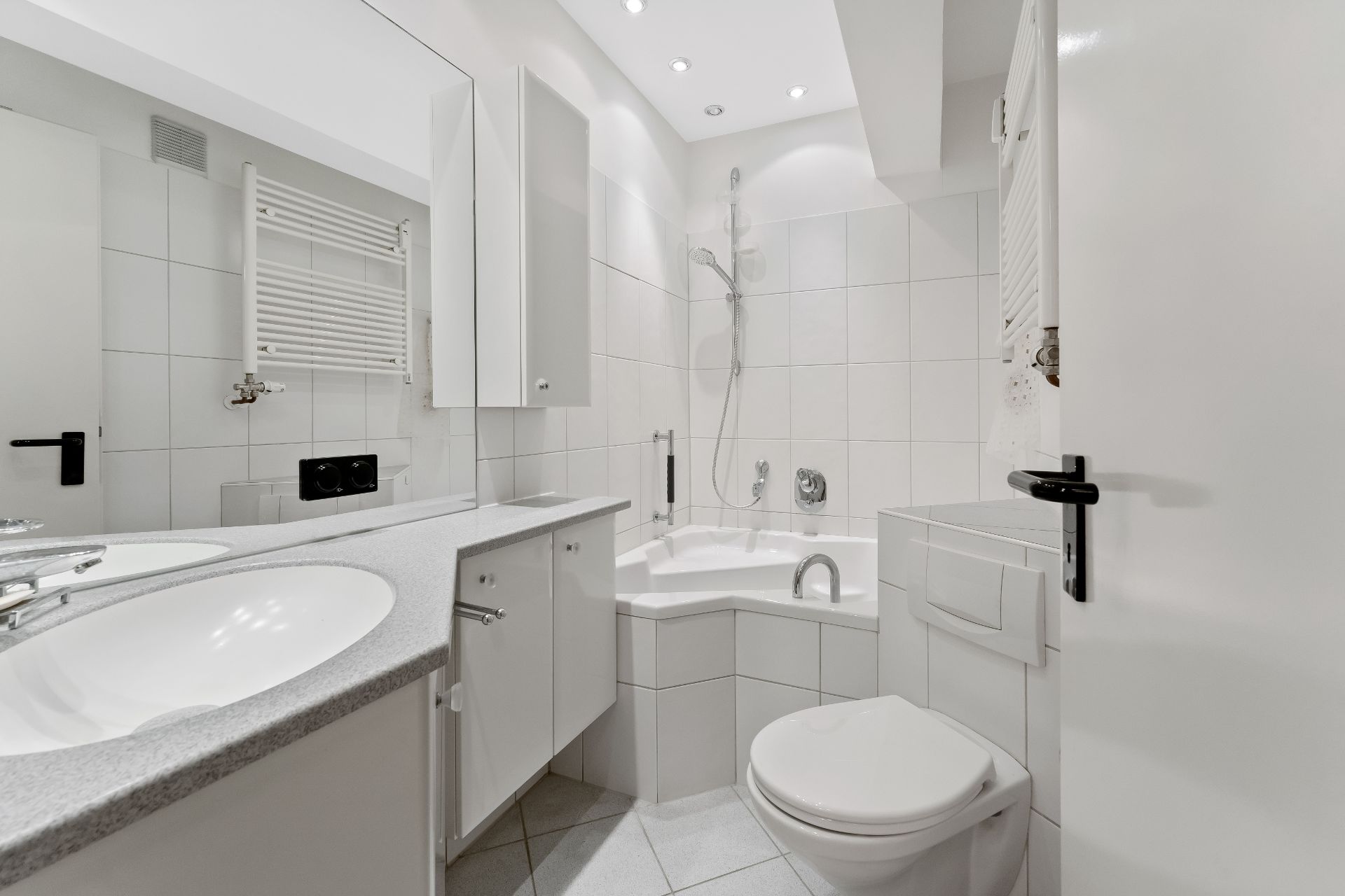 Modernes Bad mit Eckbadewanne, Dusche, Waschbecken, WC und weißen Fliesen.