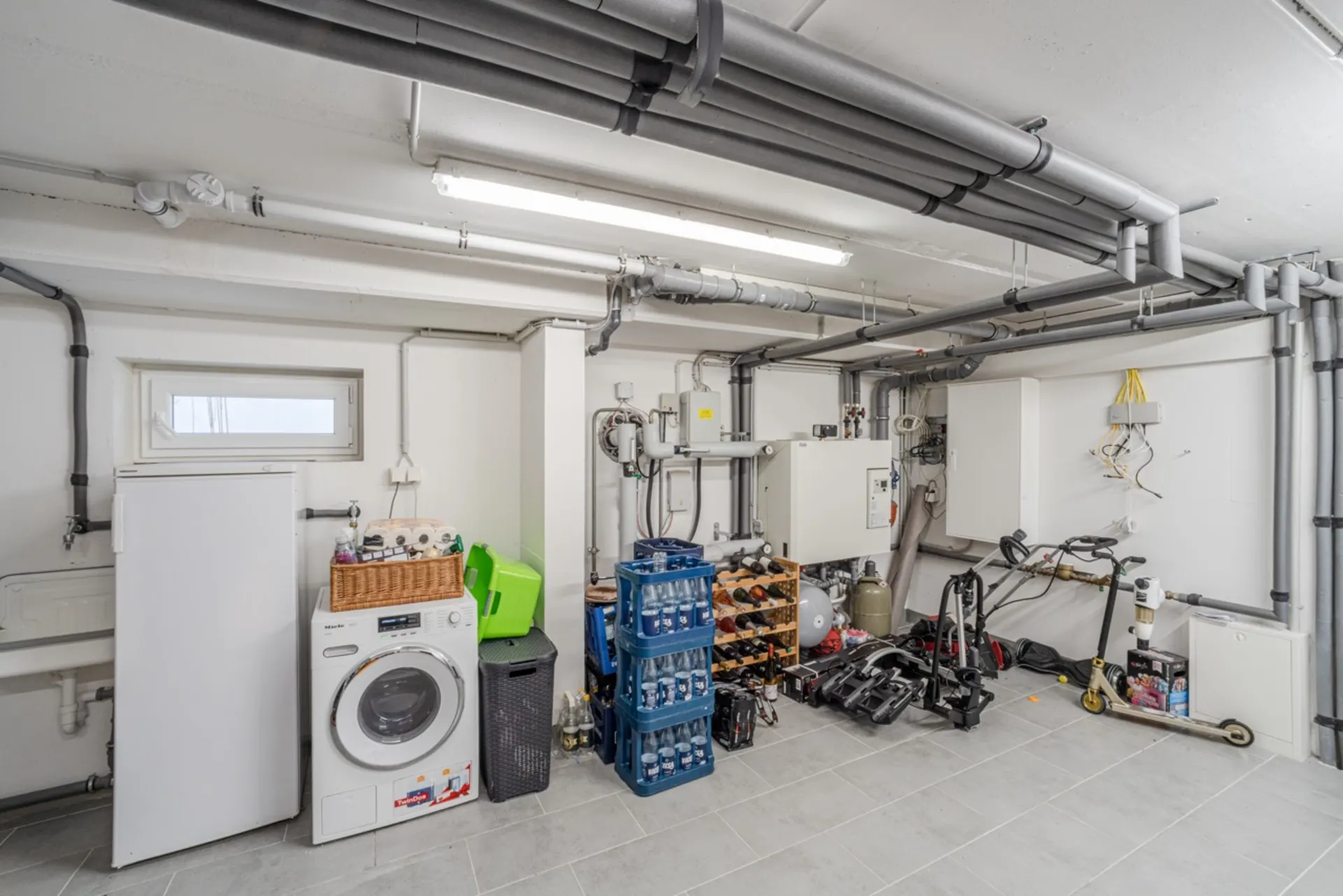 Kellerraum mit Waschmaschine, Gefrierschrank, Getränkekisten, Weinregal und einigen Werkzeugen.