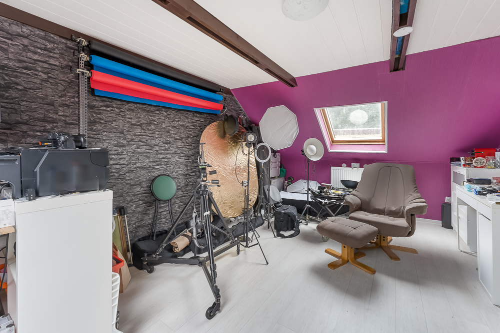 Fotostudio mit buntem Hintergrund, Lampen, Stuhl und Schreibtisch in einem Zimmer mit lila Wand.