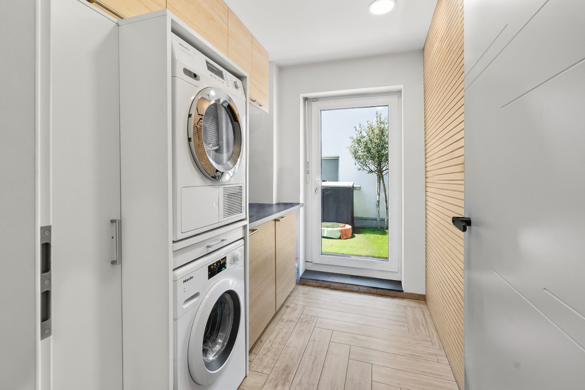 Hauswirtschaftsraum mit Waschmaschine, Trockner und Tür zum Garten.