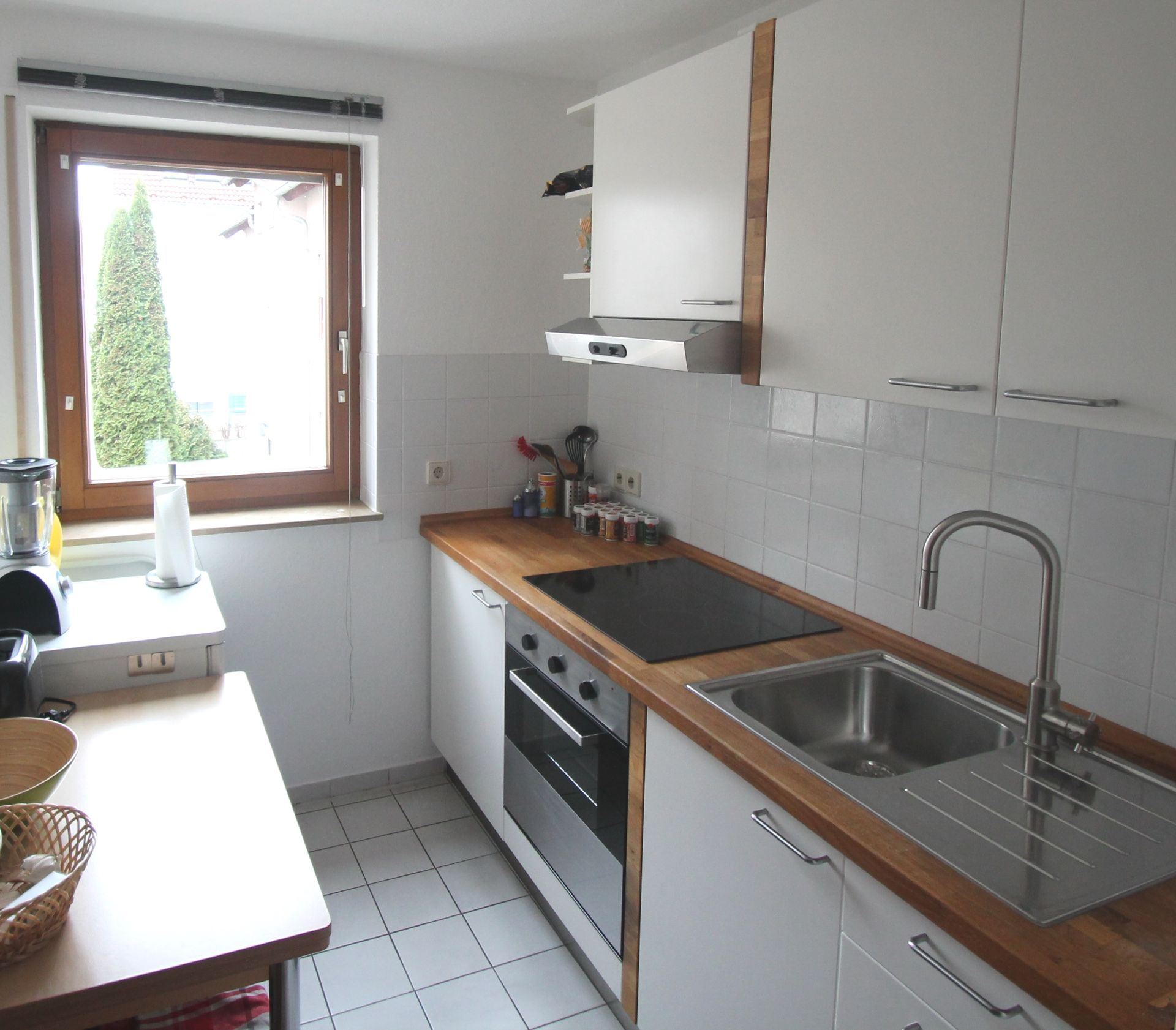 Moderne Küche mit Holzarbeitsplatte, Elektroherd, Spüle und großem Fenster.