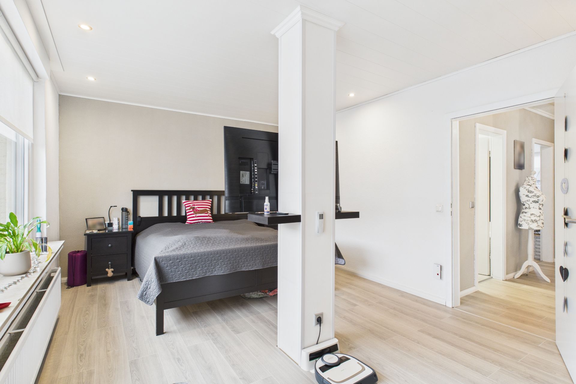 Helles Schlafzimmer mit Doppelbett, großem Fenster, TV und Holzfußboden.