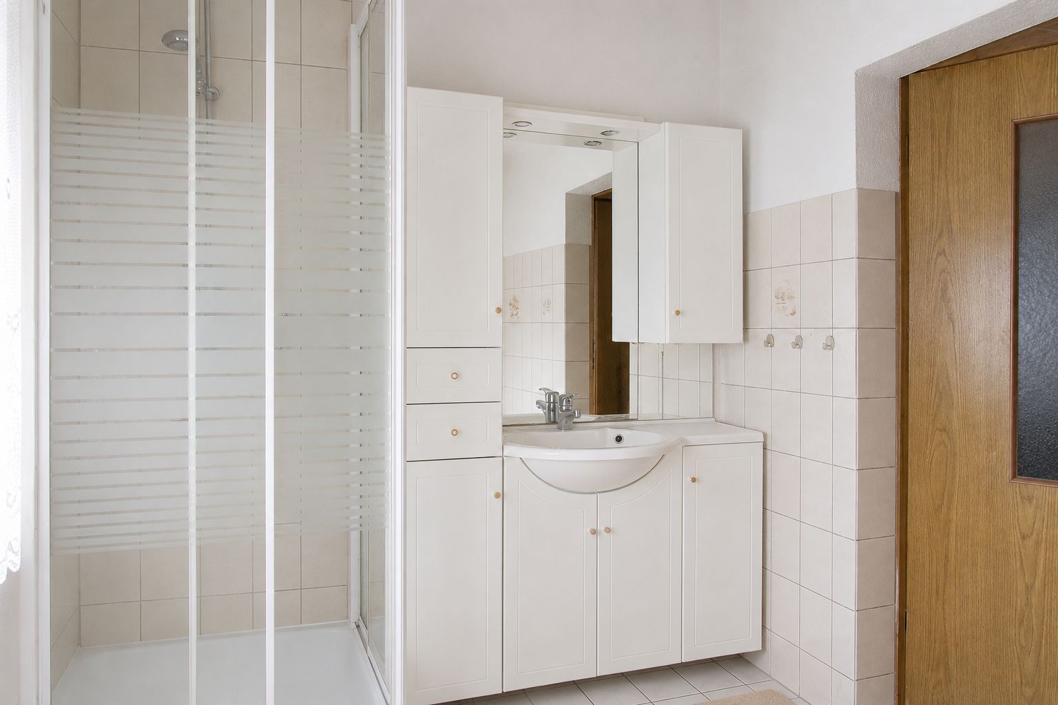 Modernes Badezimmer mit Dusche, Waschtisch, Spiegel und Holztür.