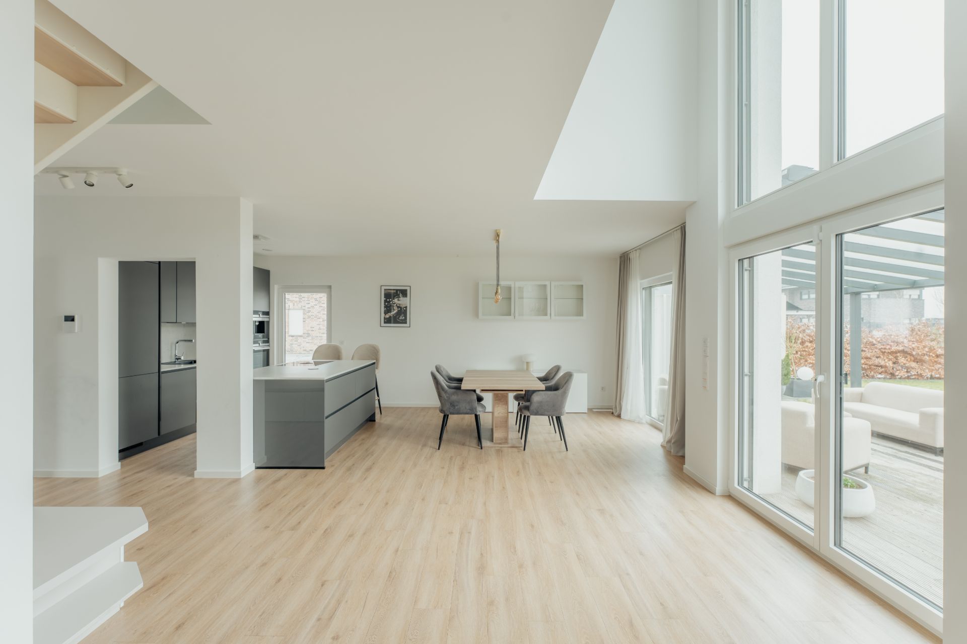 Helles Wohnzimmer mit offener Küche, Esstisch und großen Fenstern zum Garten.