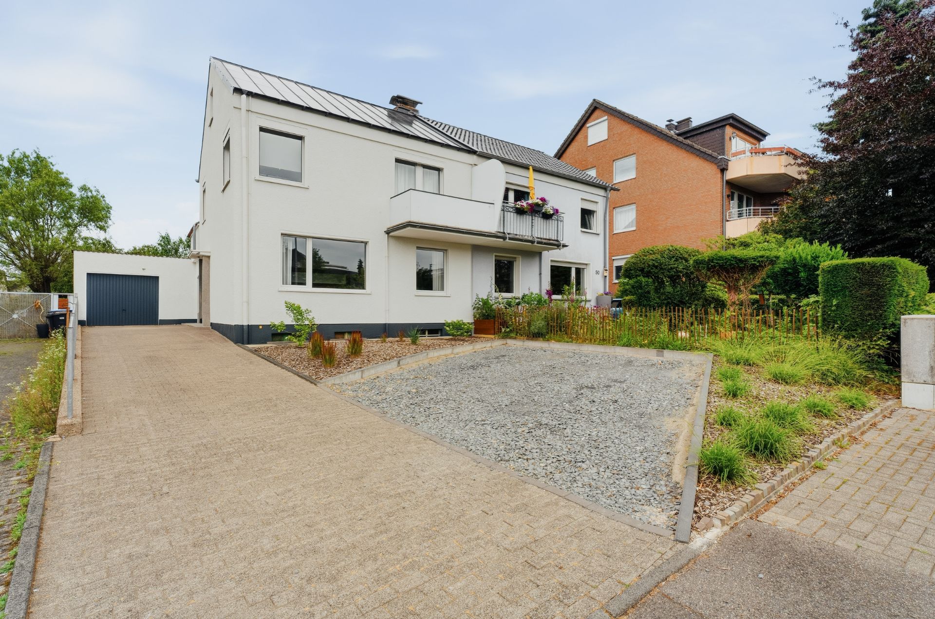 Zweistöckiges Wohnhaus mit Vorgarten, Kiesfläche und Auffahrt zu einer Garage.
