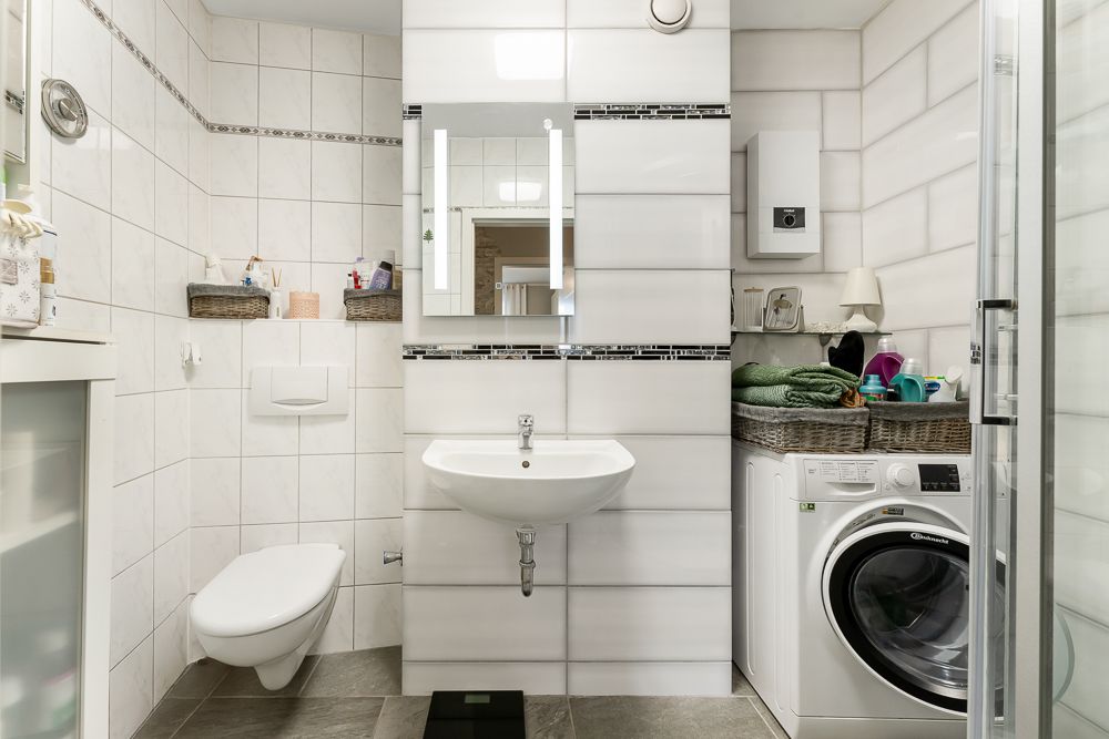 Modernes Badezimmer mit Waschbecken, Toilette, Waschmaschine und Dusche.