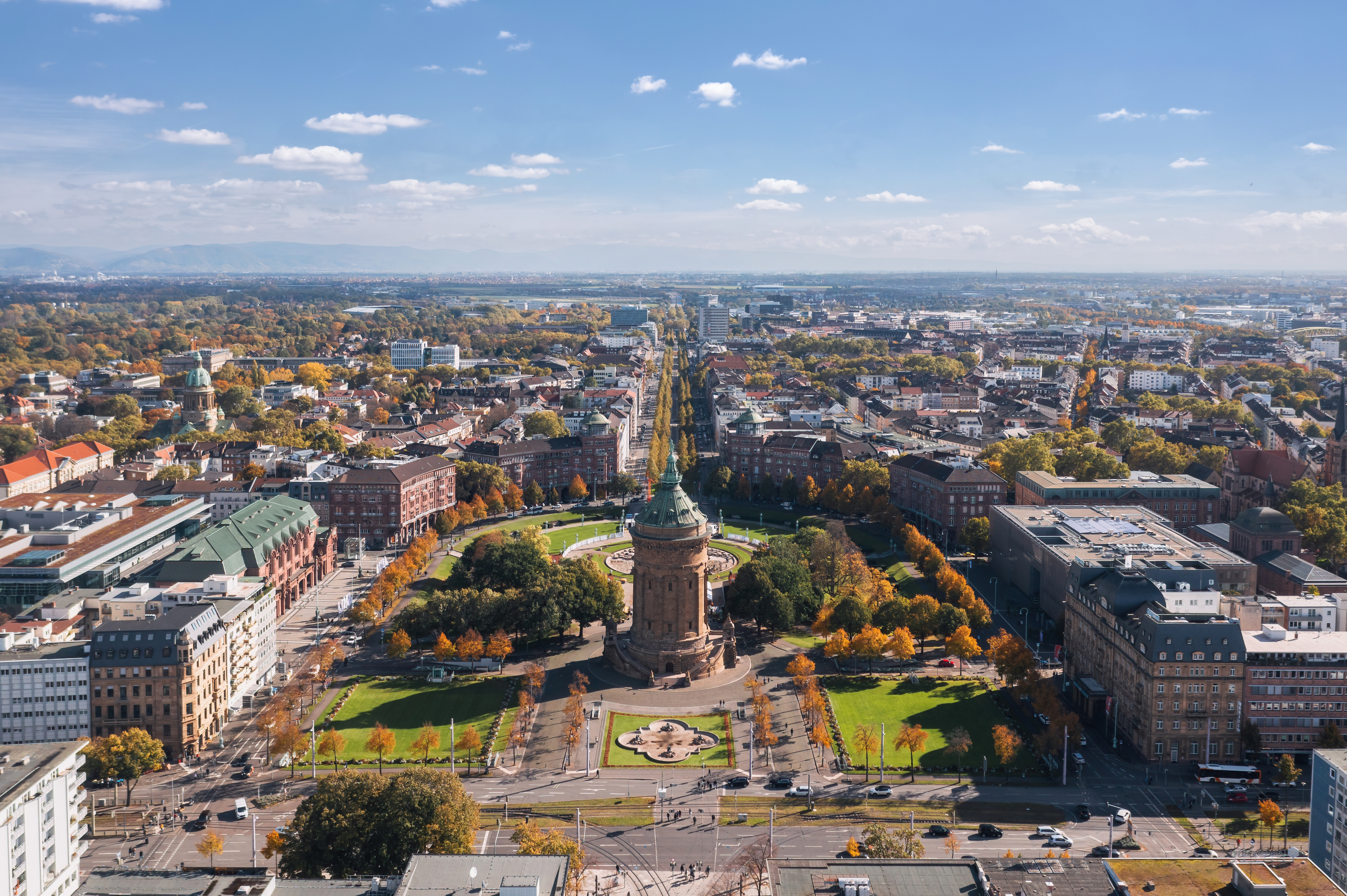 Luftaufnahme einer Stadt mit einem runden Turm inmitten eines Parks und umliegenden Gebäuden.