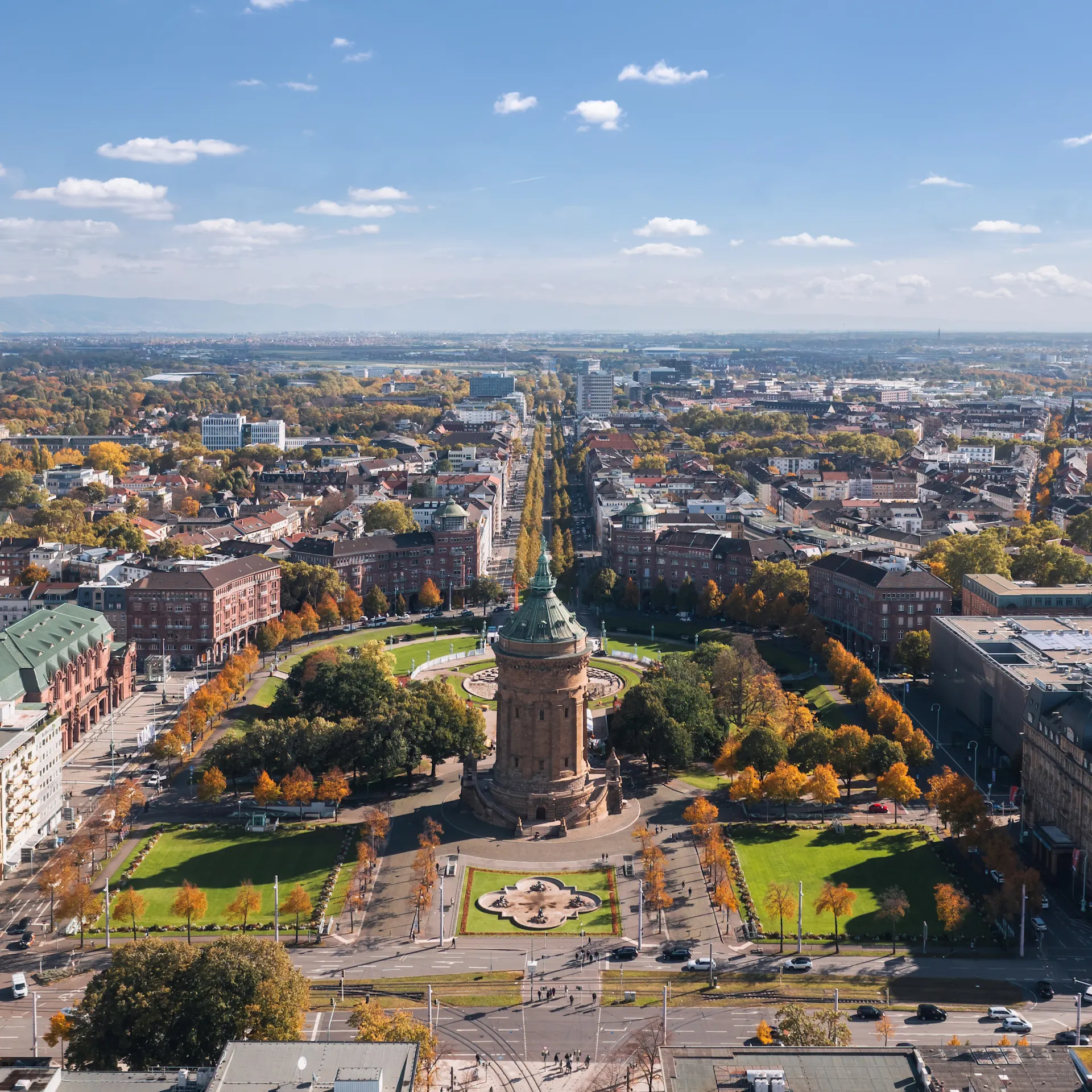Luftaufnahme einer Stadt mit einem runden Turm inmitten eines Parks und umliegenden Gebäuden.