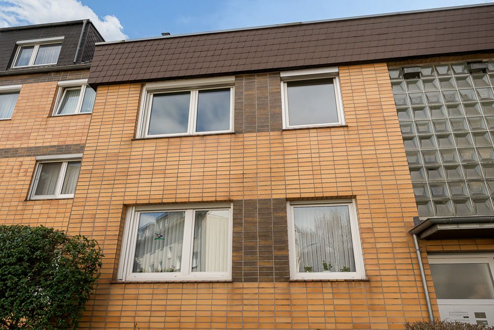 Außenansicht eines Mehrfamilienhauses mit gelber Klinkerfassade und mehreren Fenstern.
