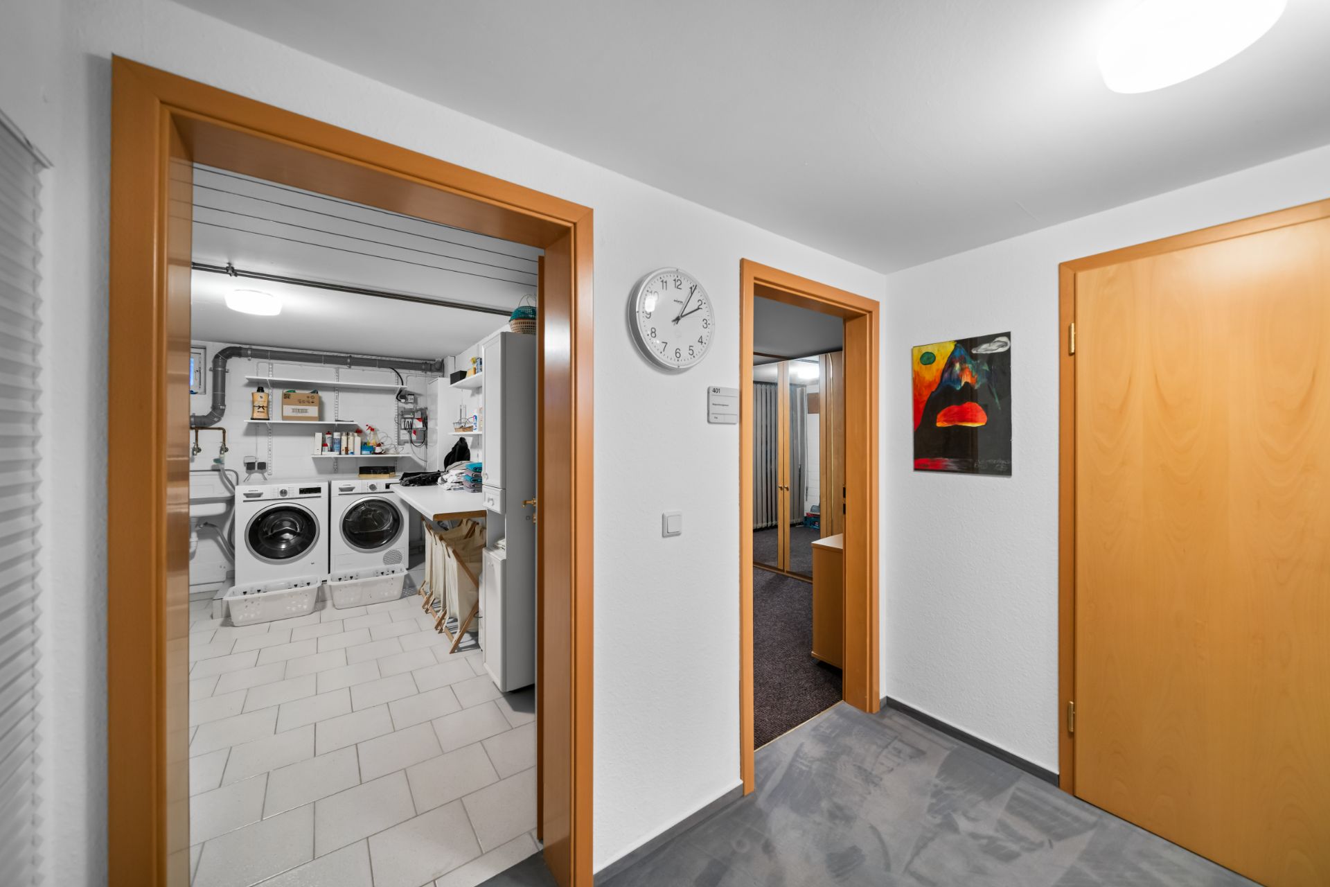 Flur mit Blick in einen Hauswirtschaftsraum mit Waschmaschine und Trockner.