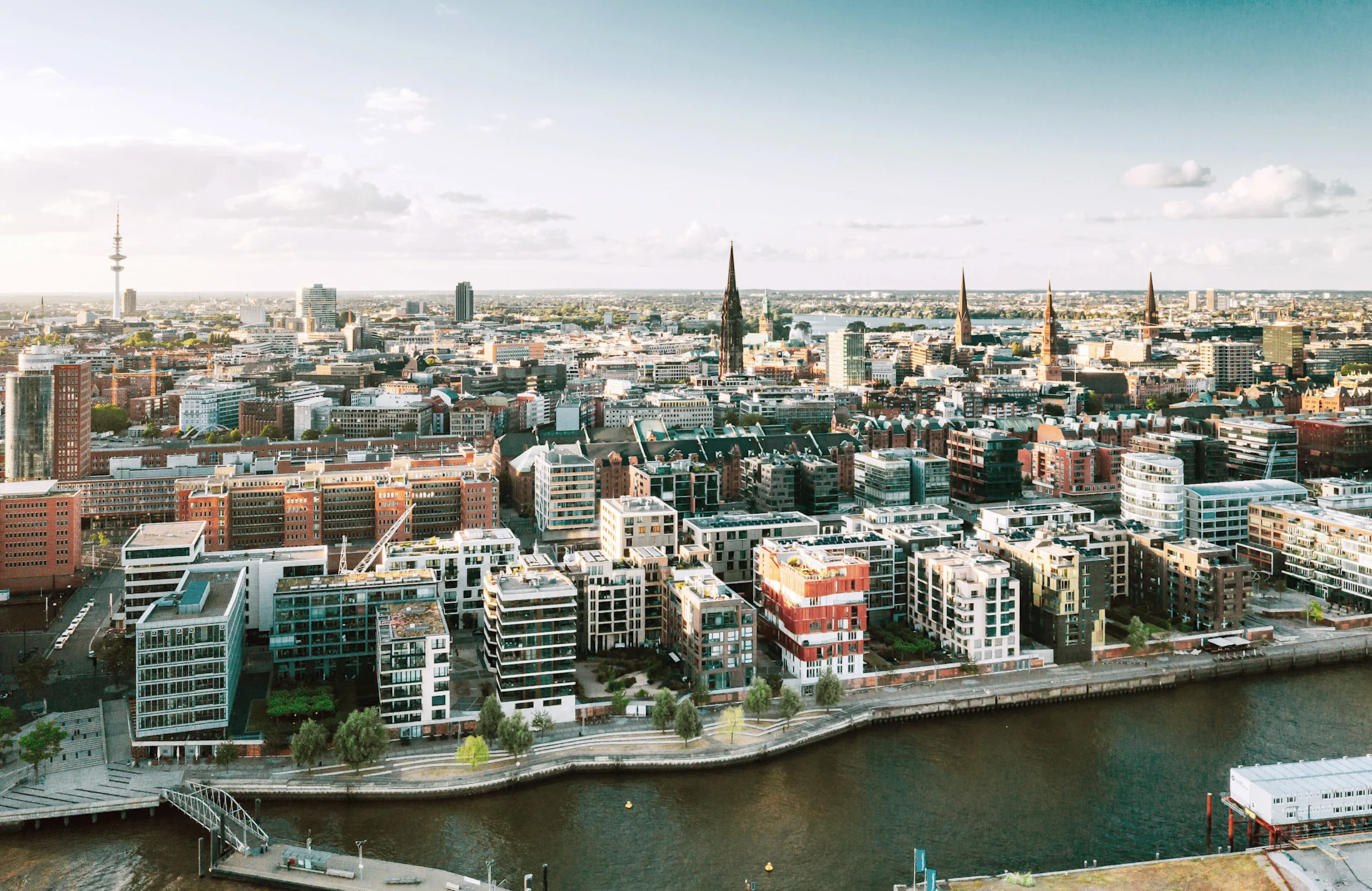 Luftaufnahme einer Stadt mit modernen Wohngebäuden und einem Fluss im Vordergrund.