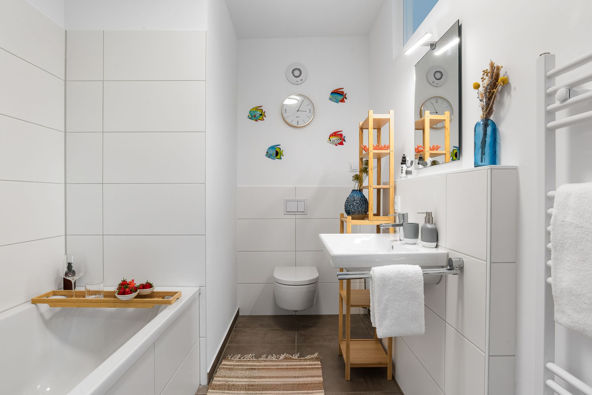 Modernes Badezimmer mit Badewanne, Waschbecken, Wandregal und Dekoration an der Wand.