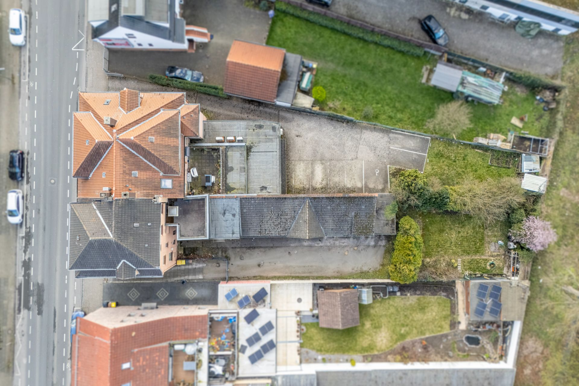 Luftaufnahme eines Wohnhauses mit Hof, Garten und angrenzender Straße.