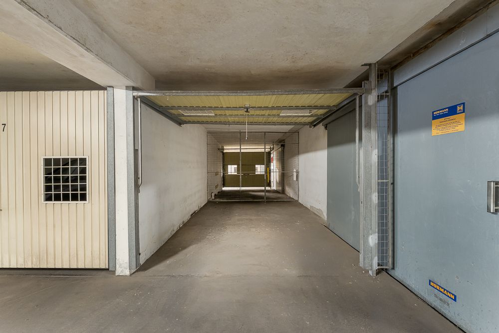 Tiefgaragenstellplatz mit offenen Toren und Betonwänden, seitlich geschlossene Parkboxen.
