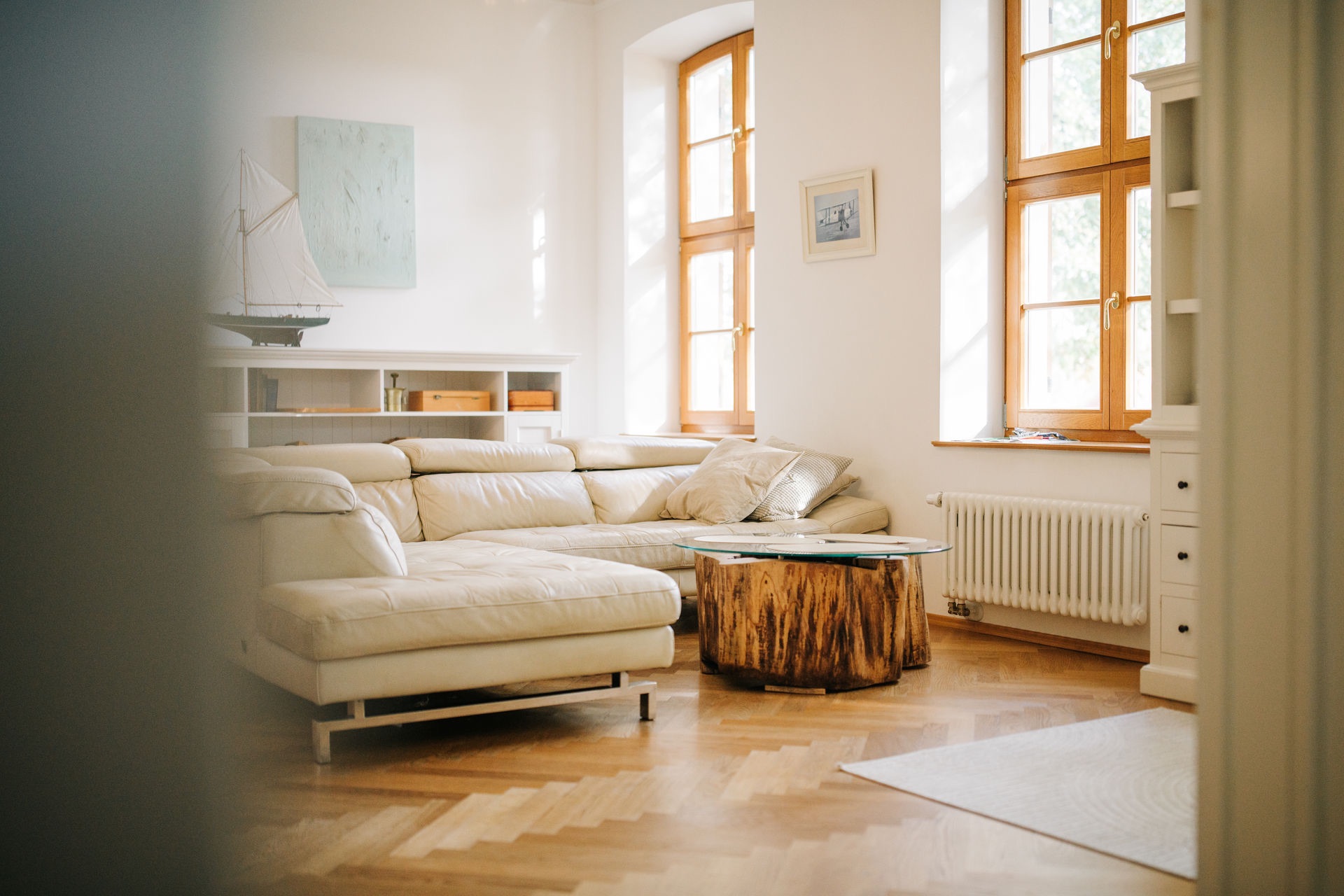 Helles Wohnzimmer mit Ecksofa, Holztisch und großen Fenstern.