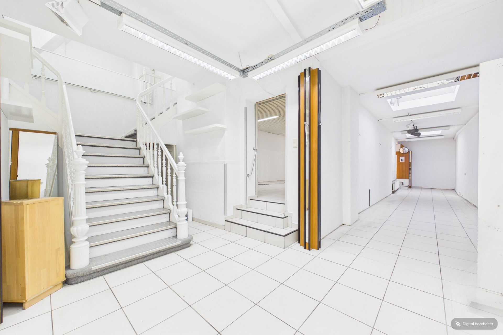 Heller Flur mit Treppe, weißen Wänden und Fliesenboden.