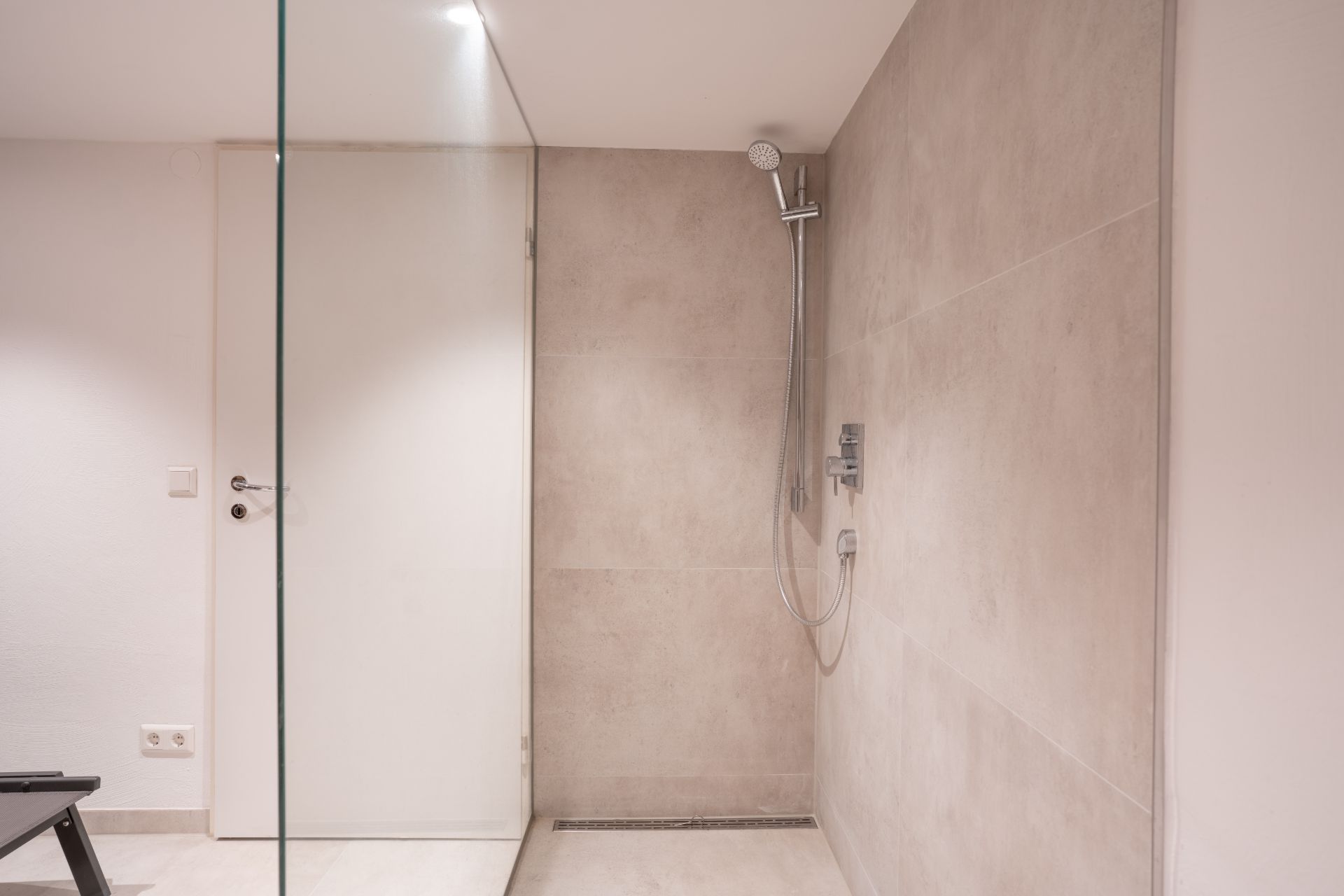 Moderne, begehbare Dusche mit Glaswand und hellem Fliesenboden.