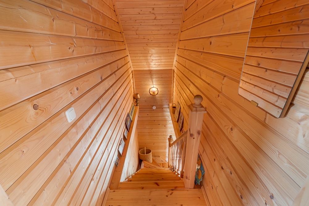 Holztreppe in einem Flur mit Holzverkleidung und Wandlampen.