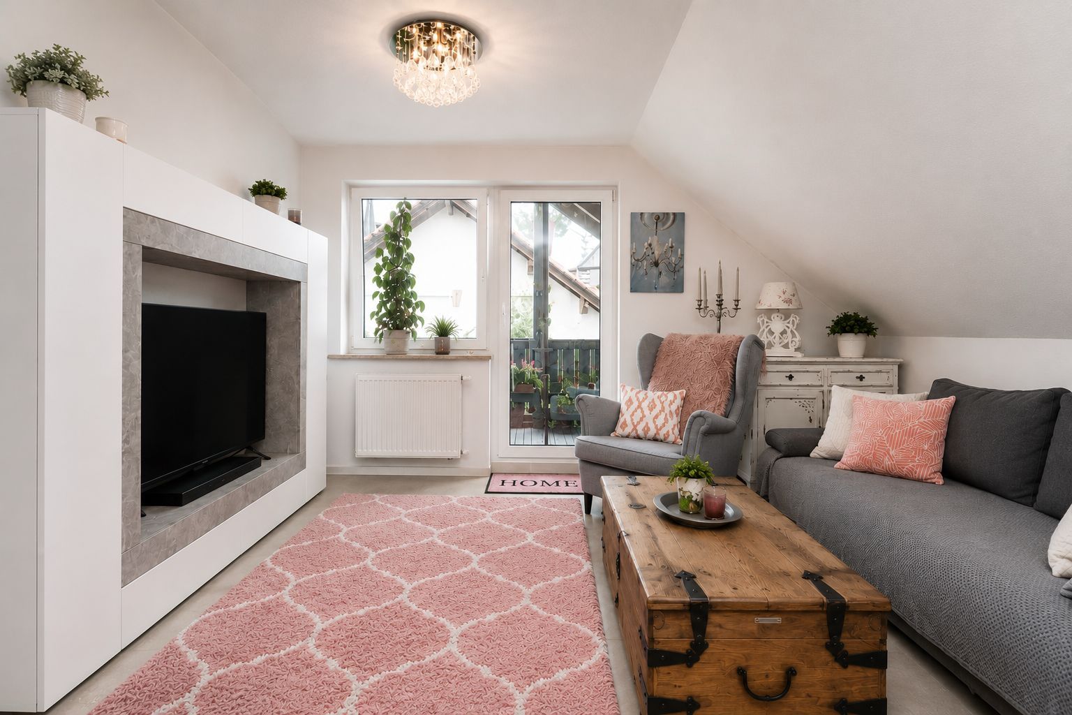 Helles Wohnzimmer mit grauem Sofa, Sessel, Holztisch und rosa Teppich vor einer Terrassentür.