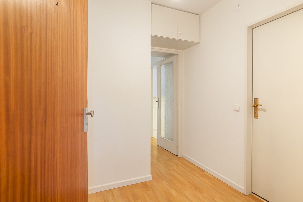 Heller Flur mit Holzboden, weißen Wänden und mehreren Türen in einer Wohnung.