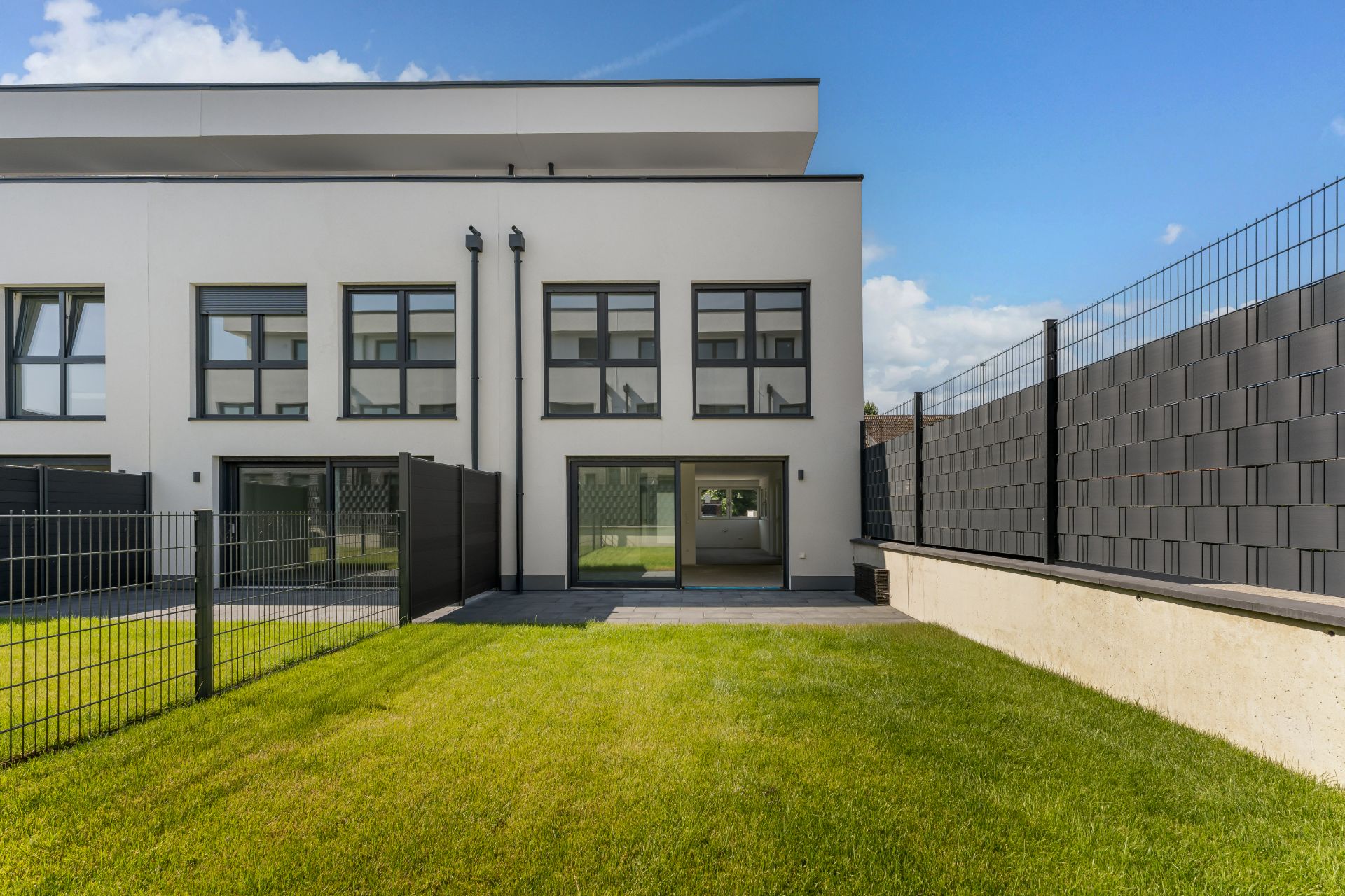 Moderne Doppelhaushälfte mit großem Garten, Terrasse und großen Fenstern.