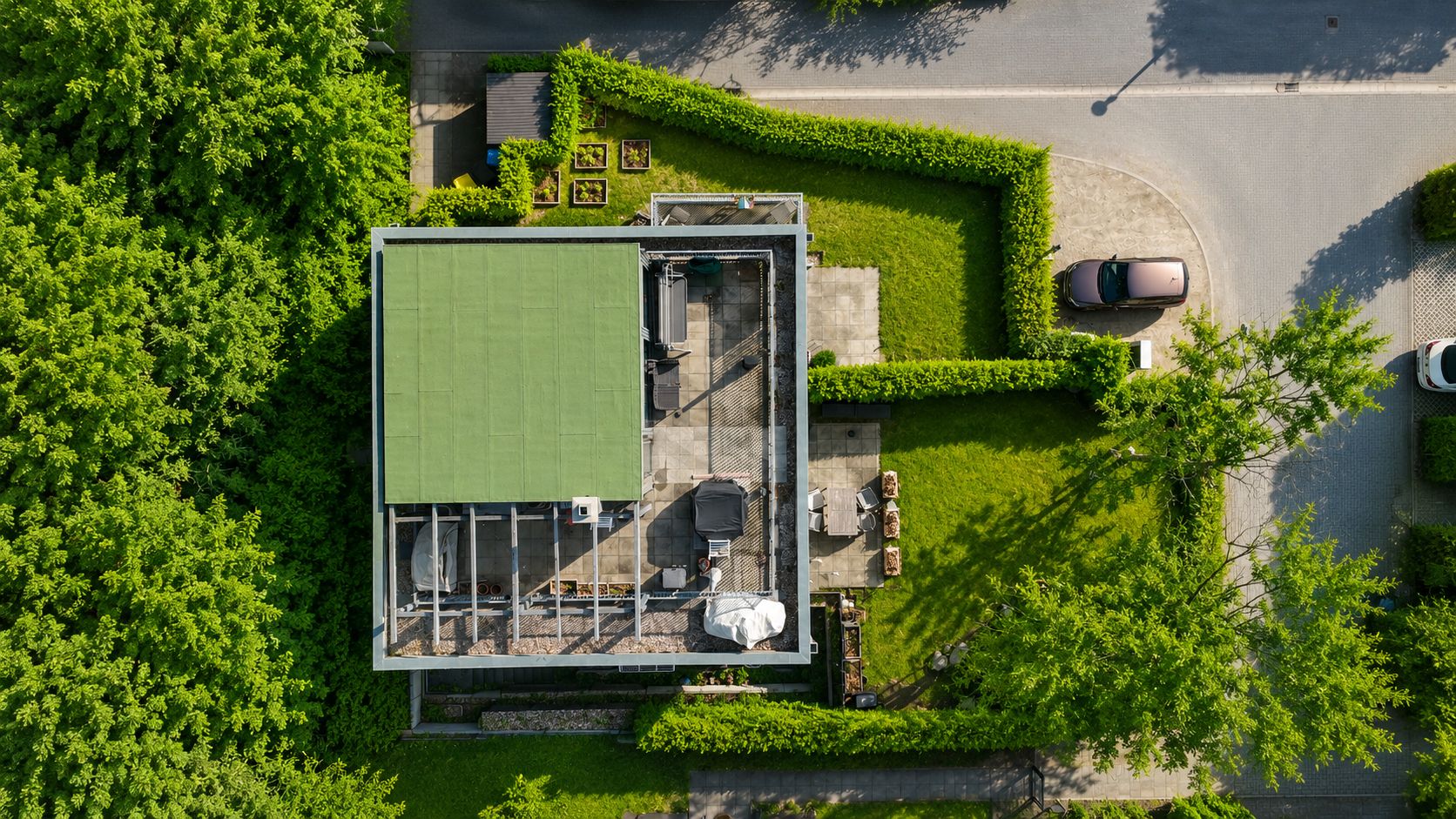 Luftaufnahme eines modernen Hauses mit Garten, Terrasse und angrenzender Straße.