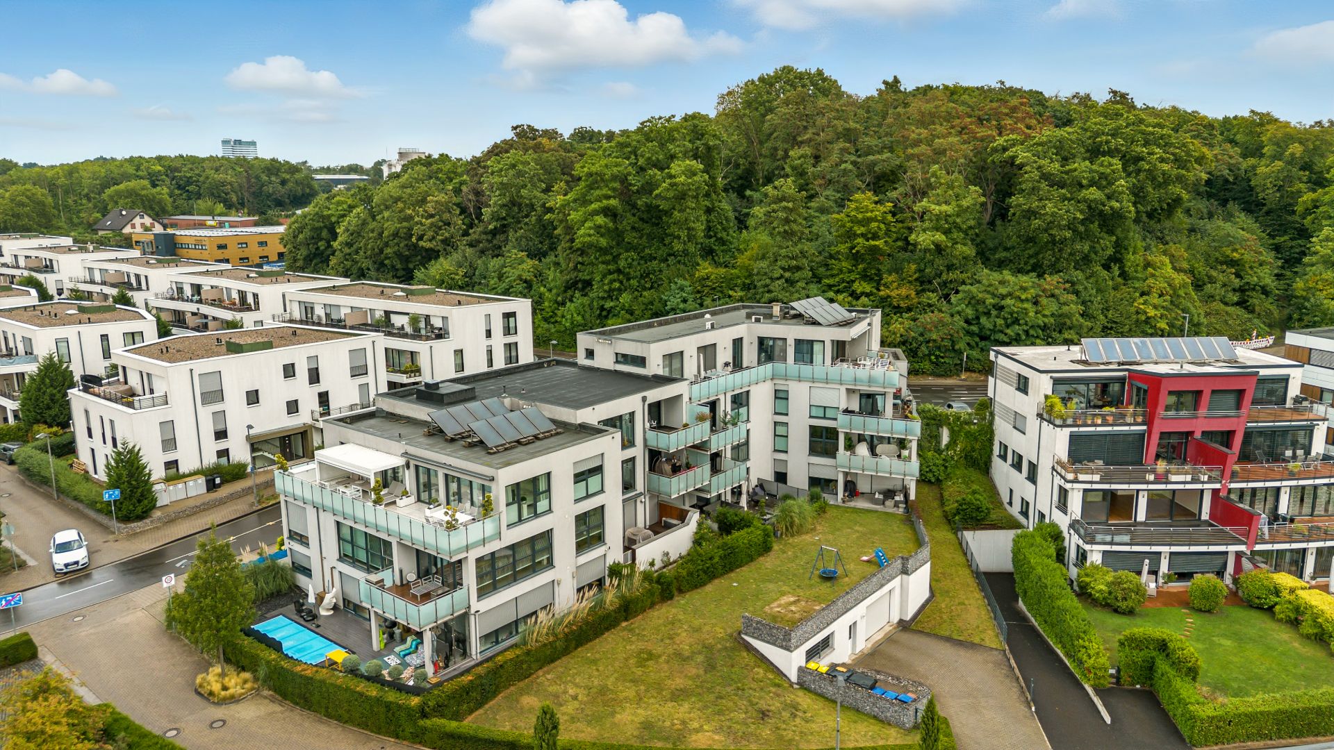 Mehrere moderne Wohngebäude mit Balkonen, umgeben von Gärten und Bäumen.