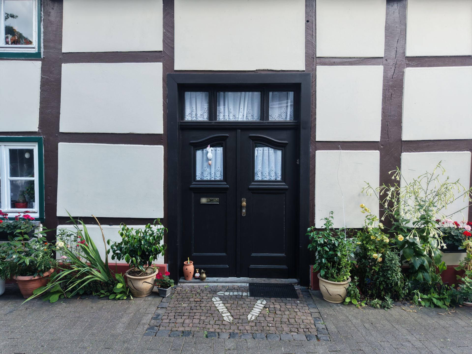 Eingangstür eines Fachwerkhauses mit Pflanzen in Töpfen auf beiden Seiten.