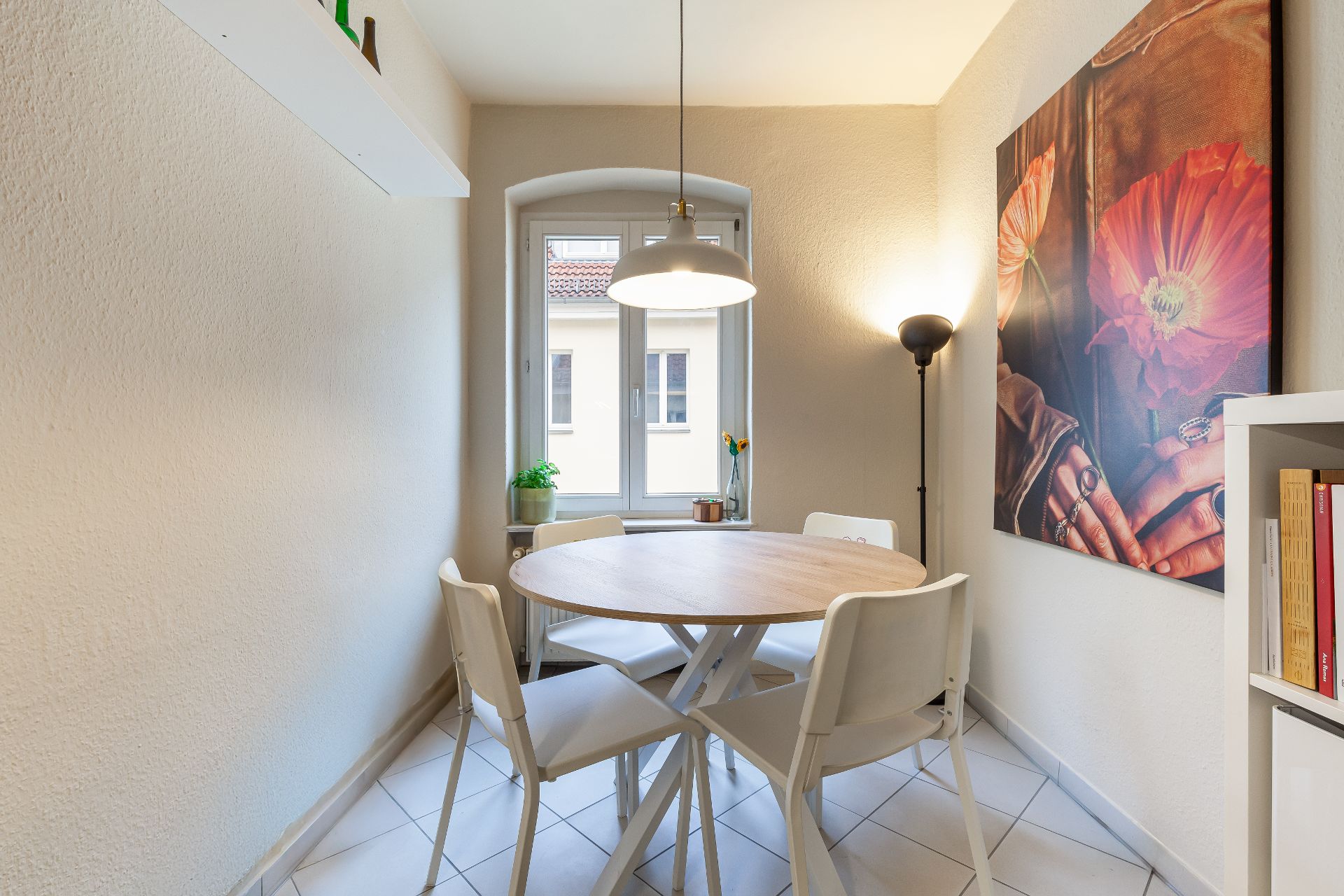 Kleiner Essbereich mit rundem Tisch, vier weißen Stühlen und großem Fenster.