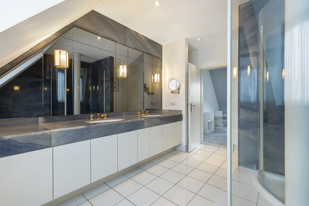 Modernes Badezimmer mit Doppelwaschbecken, großen Spiegeln und einer Glasdusche.