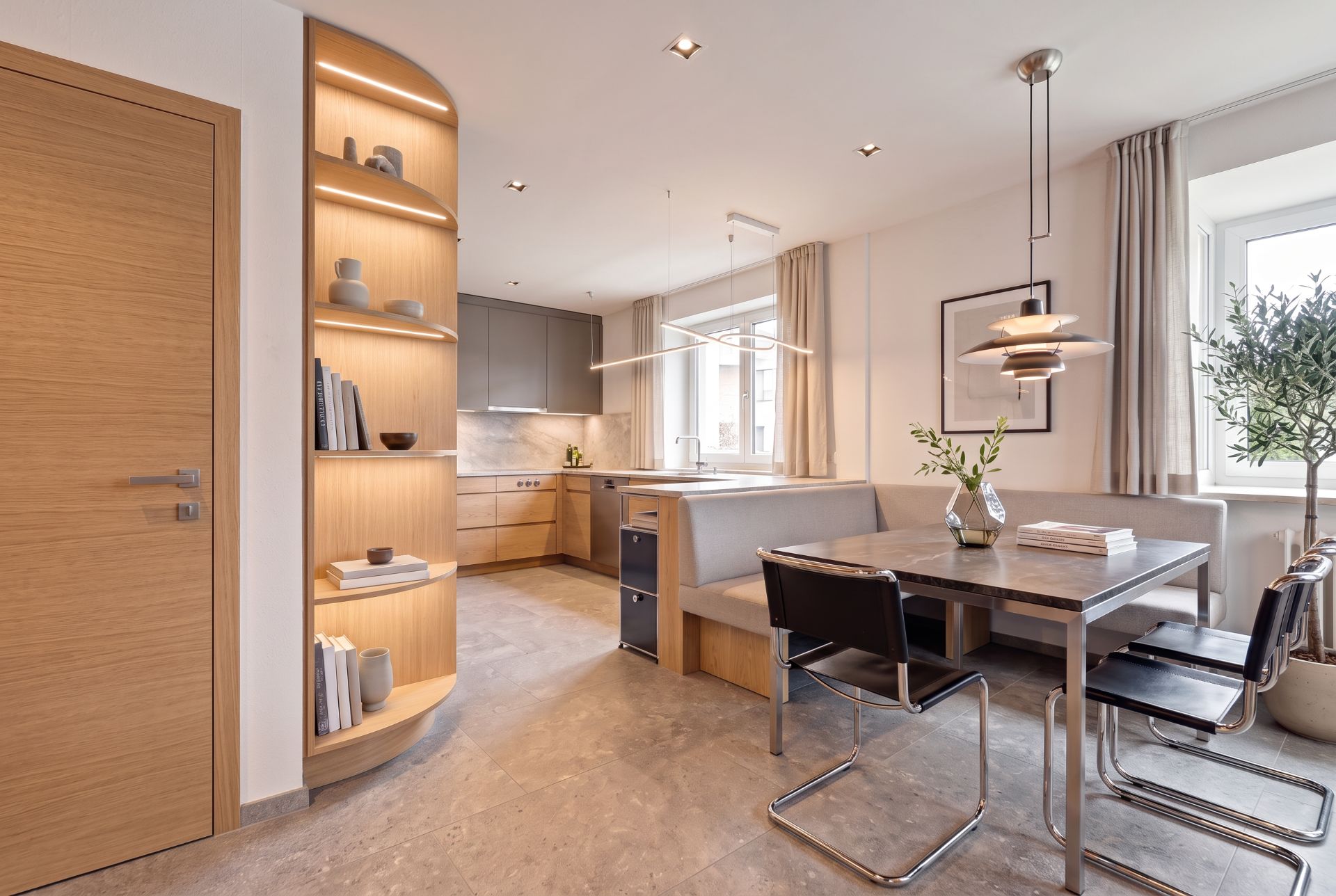 Moderne Wohnküche mit Essbereich, Eckbank, Regal und großen Fenstern.