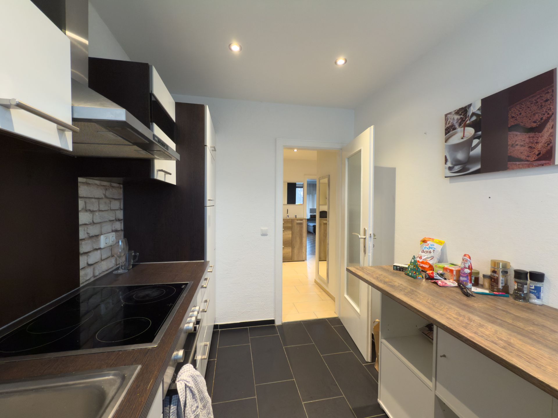 Moderne Küche mit dunklen Fliesen, Holztresen und weißen Schränken, mit Snacks auf der Arbeitsfläche.