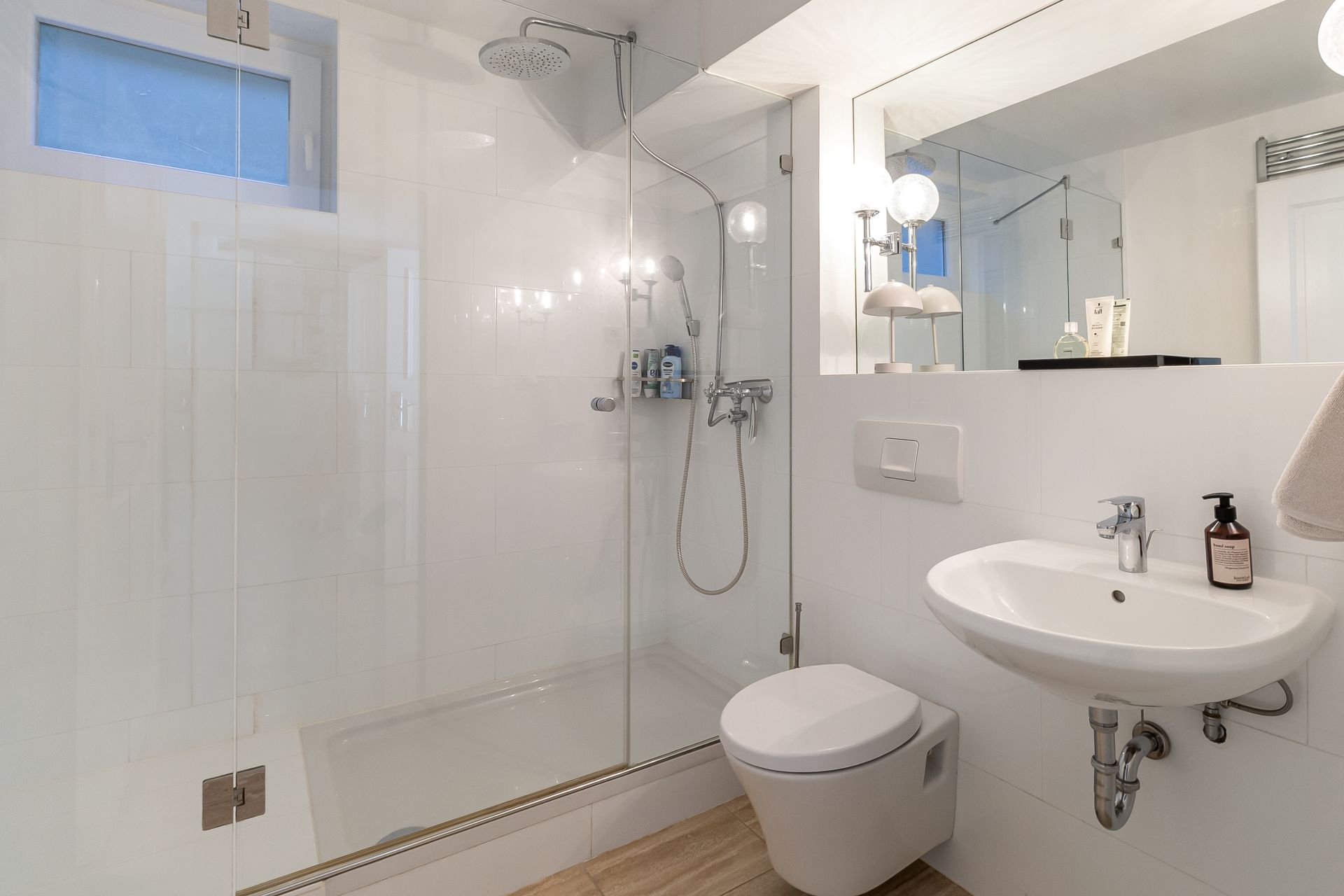 Modernes Badezimmer mit Dusche, WC, Waschbecken und großem Spiegel.