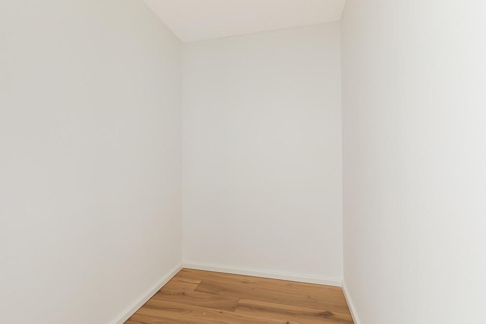 Kleiner leerer Raum mit weißen Wänden und Holzfußboden.