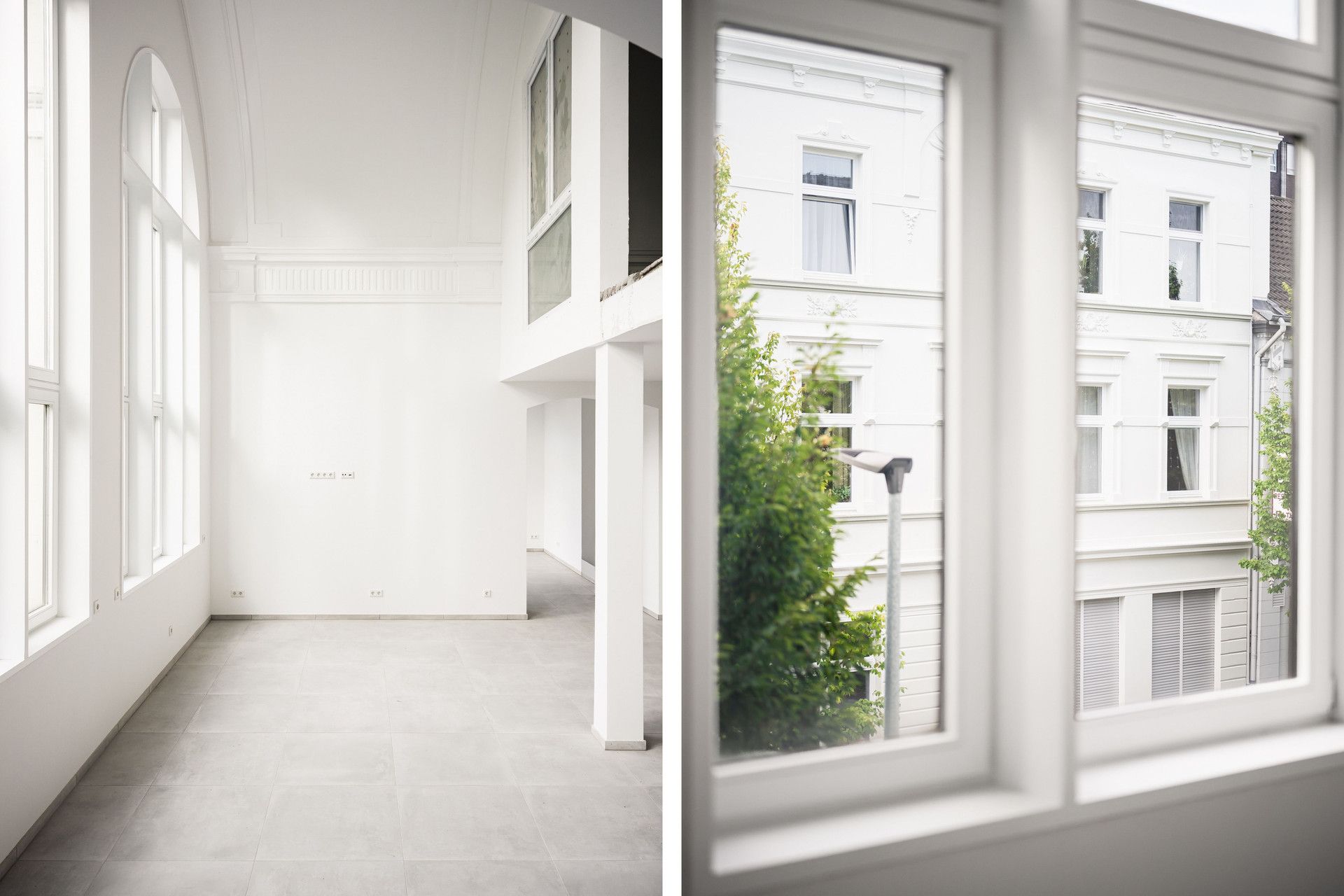 Heller Wohnraum mit großen Fenstern und Blick auf die Fassade eines Nachbarhauses.