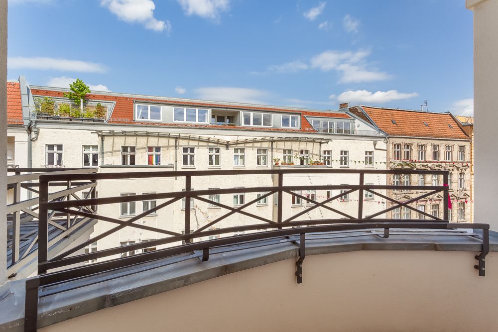 Balkon mit Metallgeländer, Blick auf benachbarte Wohngebäude mit roten Dächern.