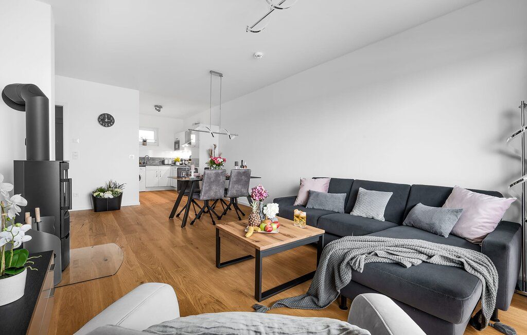 Modernes Wohnzimmer mit Sofa, Couchtisch, Essbereich und offener Küche auf Holzfußboden.
