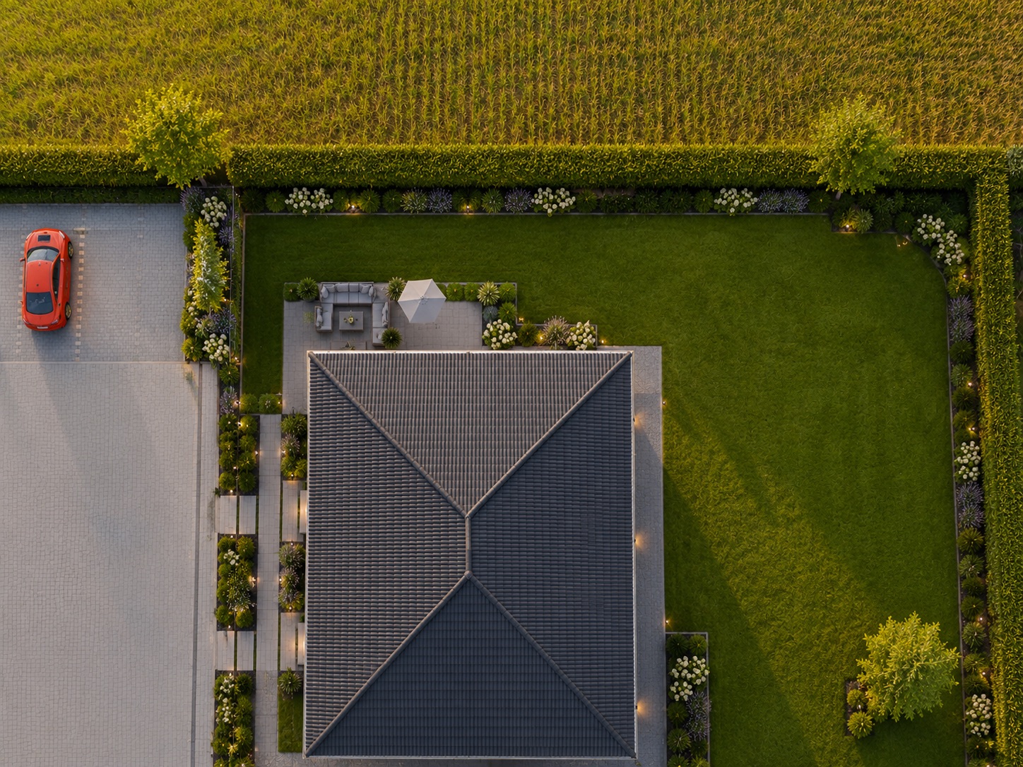 Luftaufnahme eines Hauses mit Garten, Terrasse und einem geparkten roten Auto auf Auffahrt.