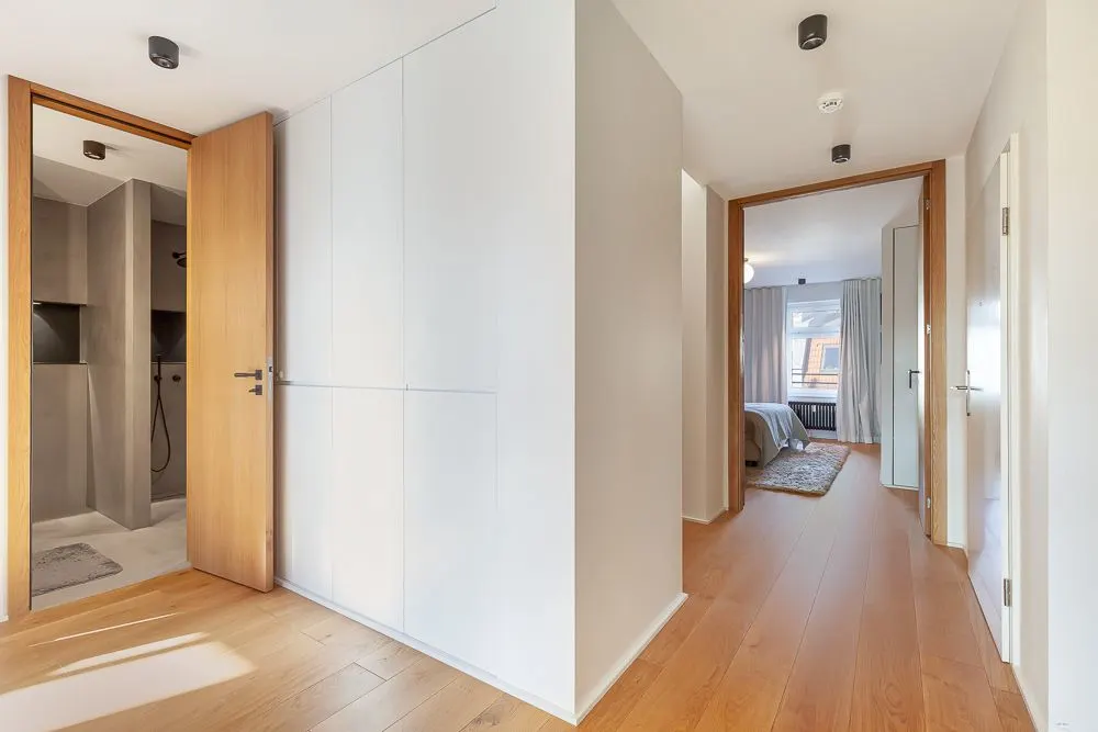 Heller Flur mit Holzboden, Türen zu Bad und Schlafzimmer, Einbauschränke an der Wand.